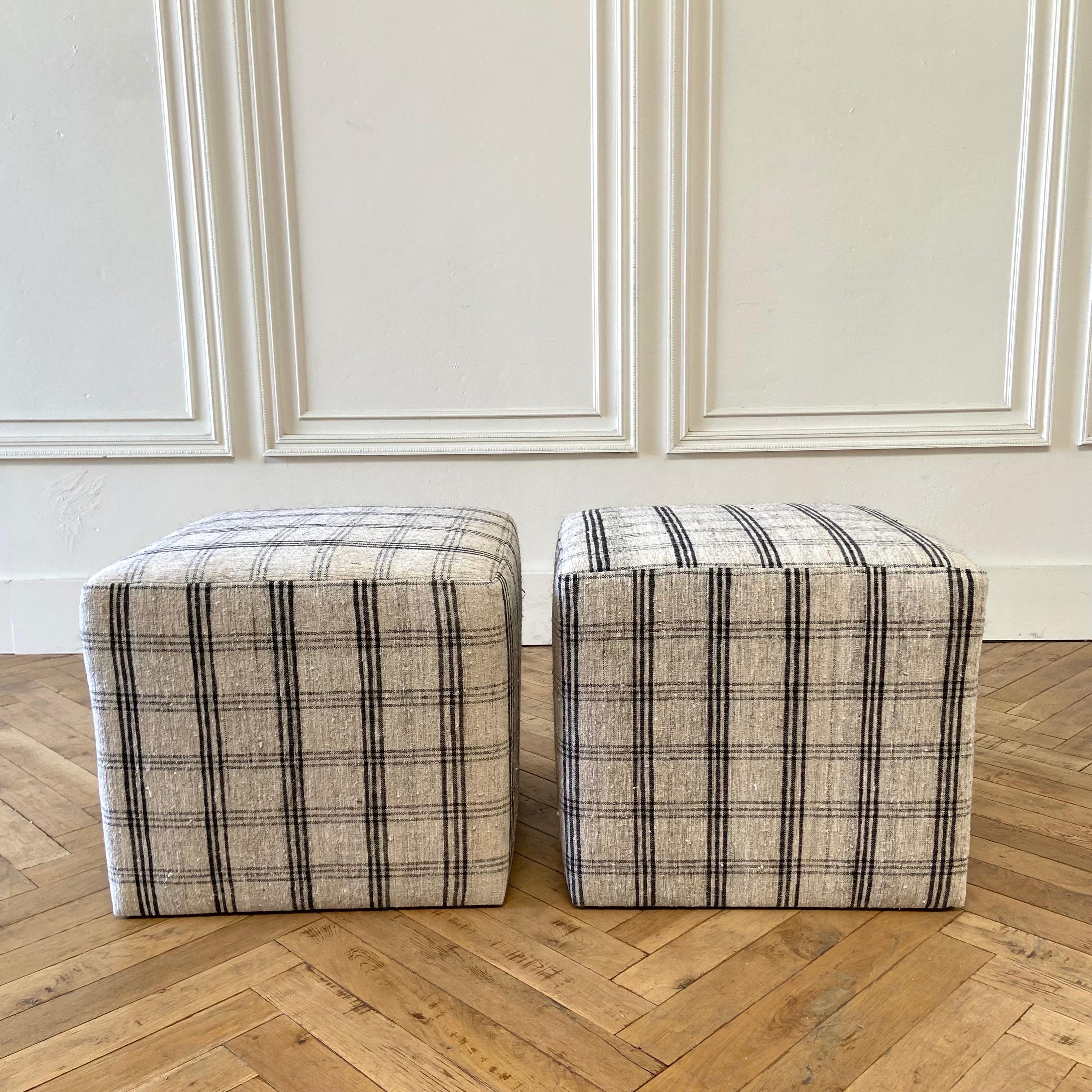 Vintage rug upholstered cube ottomans
Pair cube ottomans 21” x 21” x 18”h
constructed from a solid wood frame with foam top, upholstered in a vintage one of a kind rug. 
Colors: off white, grayish tone background with dark colored plaid pattern.