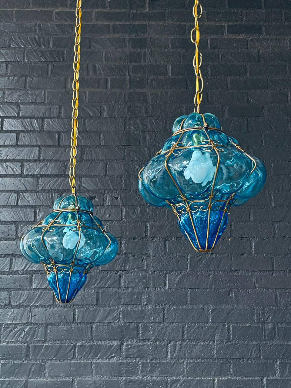 Estado: Estado original de época 
Materiales: Vidrio turquesa soplado a mano, jaula de metal dorado, cadena y dosel de latón
Estilo: Renacimiento español

Este llamativo par de faroles colgantes vintage presenta tulipas de cristal de burbujas