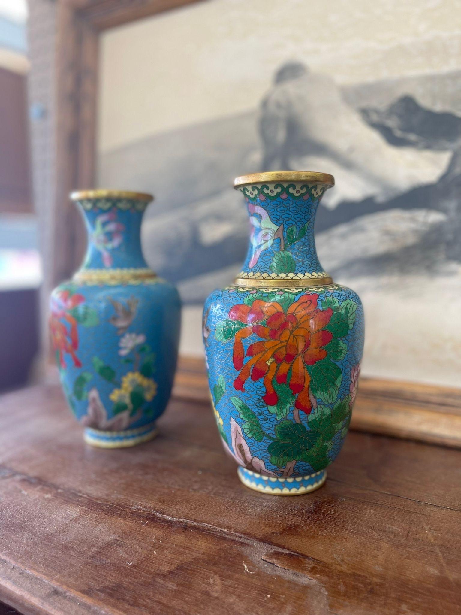 Set of Two Vases, Featuring Bright Orange, Pink, and Yellow Flower’s, Birds and a Blue Background. Unsigned, Gold Colored Cloud Outlines.

Dimensions. 5 W ; 5 D ; 9 H