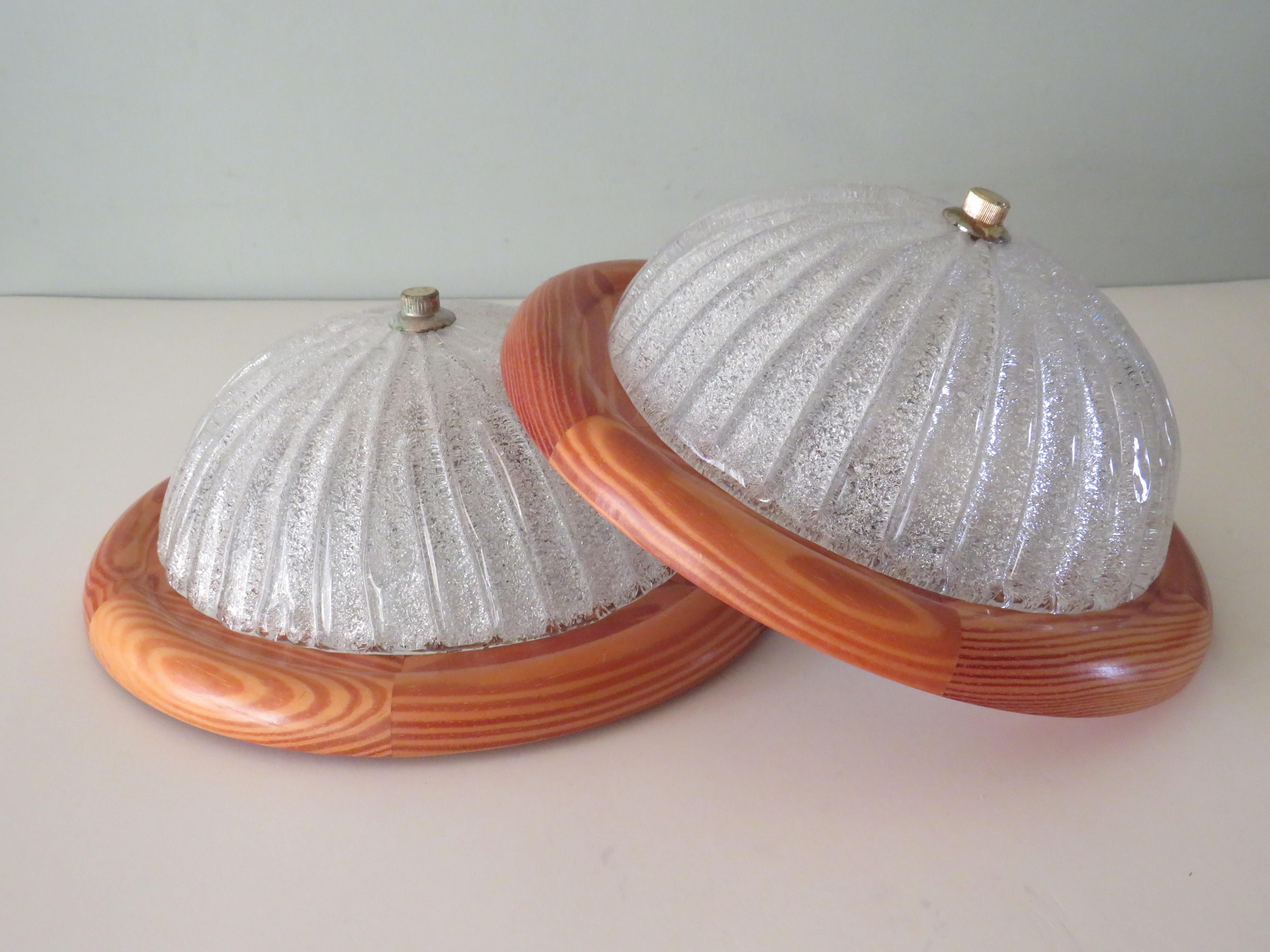 The lamps have a round pine wooden wall plate on which a half glass ribbed sphere of glass, with ice glass effect is placed.
They both have an E 27 fitting and are in good condition, the Massive label is present. The metal cap has patina due to its