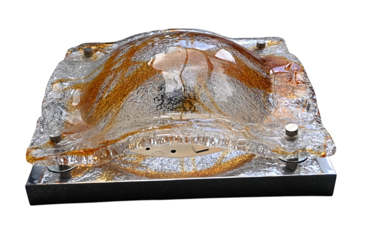 Cette paire d'appliques a été conçue par Toni Zuccheri pour Mazzega, Italie, dans les années 1960. Elle est réalisée en verre de Murano épais, ondulé, ambré et transparent, monté sur une plaque murale chromée. Le verre est fabriqué à la main avec de