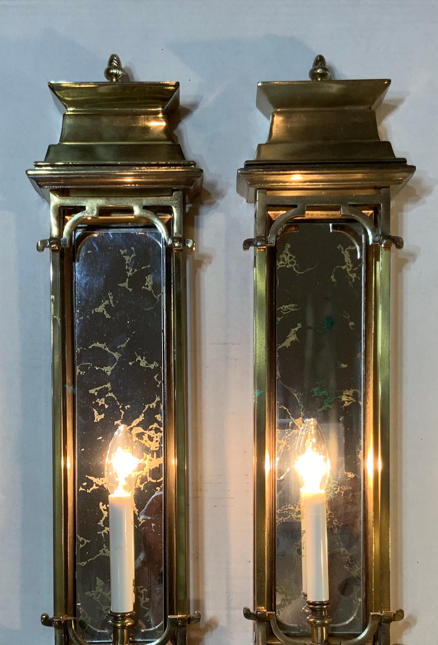 Beautiful pair of wall sconces made of part solids brass, and part brass patinated metal, frosted decorative glass mirror backing, and one 60/watt light each. Attractive pinecone finial on the top and the bottom, one of a kind longish pair of scones.