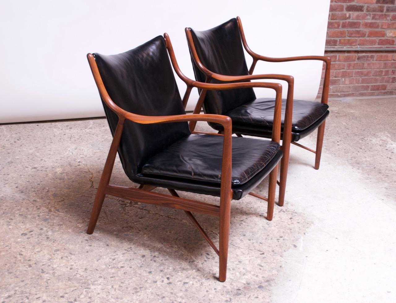 Pair of iconic circa 1950s Finn Juhl for Baker lounge chairs in walnut with original black leather upholstery (Baker model #409 1/2; the former Neils Vodder version is model #NV-45).
Sculpted walnut frames feature delicate contours and gracefully