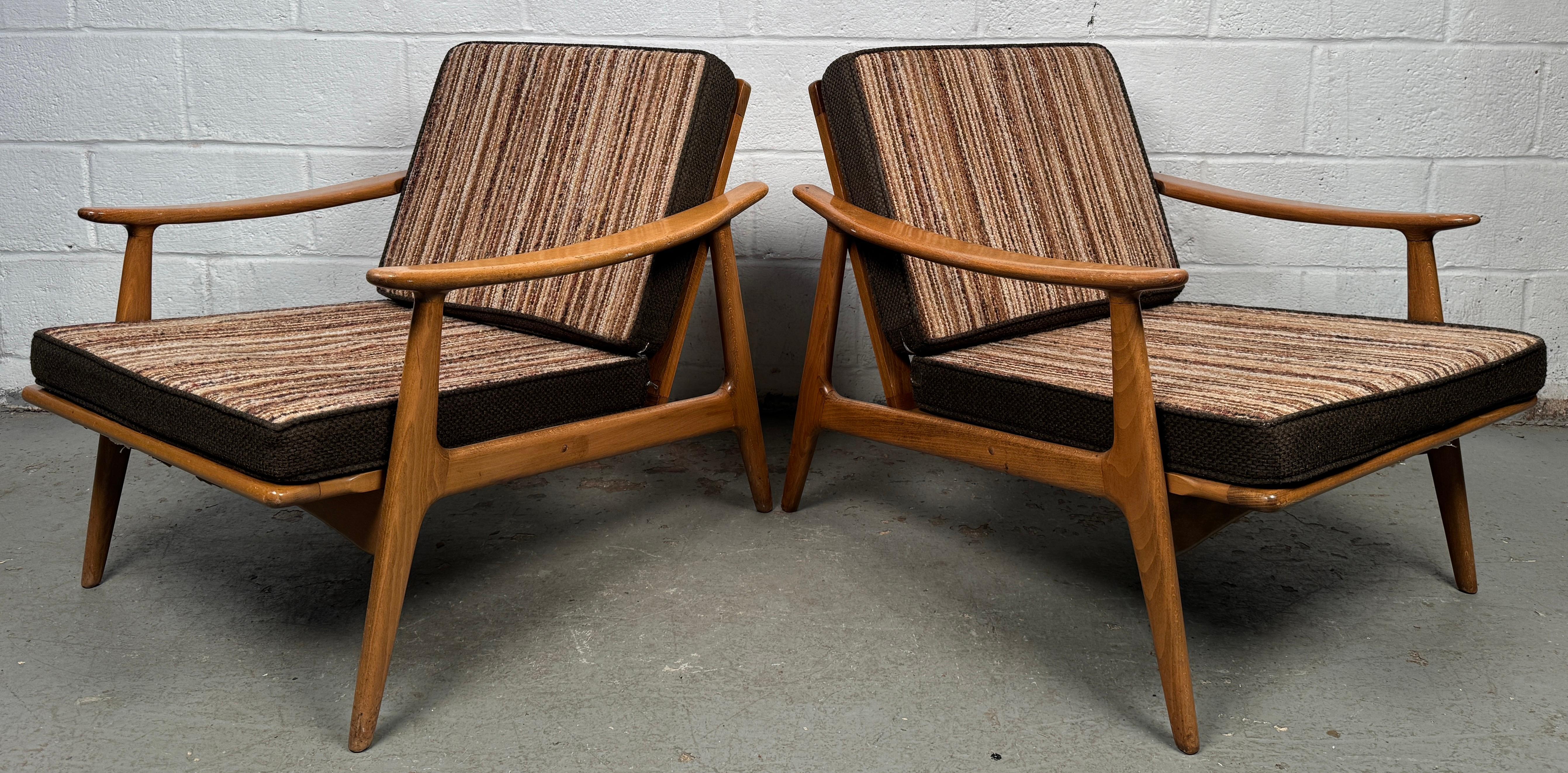 Dieses zeitlose und einladende Paar Vintage-Sessel mit Spindellehne aus Nussbaum fängt die Essenz der Handwerkskunst aus der Mitte des Jahrhunderts ein. Mit ihren schön geformten Armlehnen, die nahtlos in den Rahmen übergehen, bieten diese Stühle