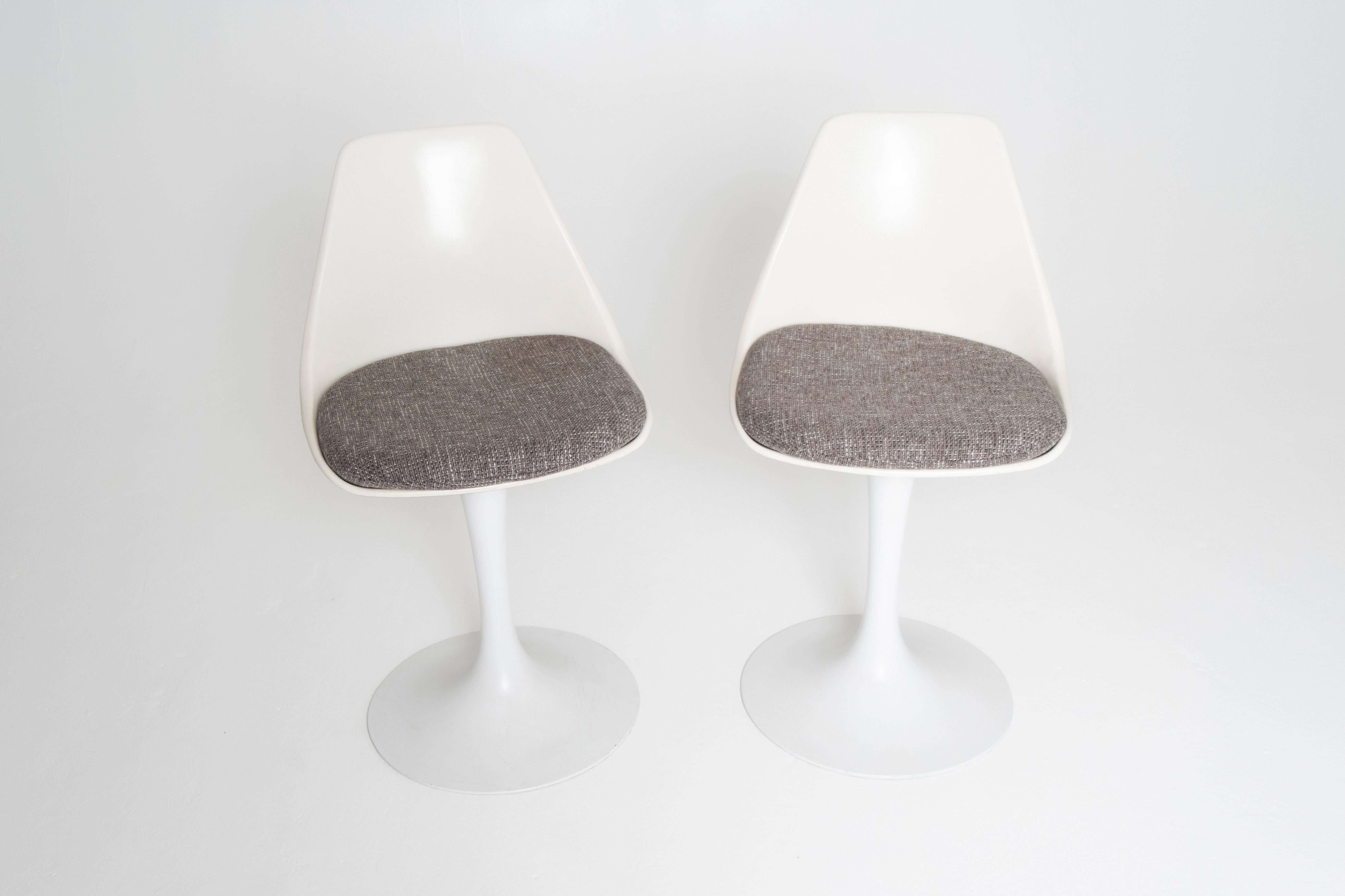 A classic pair of counter-height tulip chairs manufactured by Burke Inc. in the 1960s, inspired by the iconic designs of Eero Saarinen. These vintage chairs feature molded white fiberglass shells mounted on powder-coated pedestal bases , offering