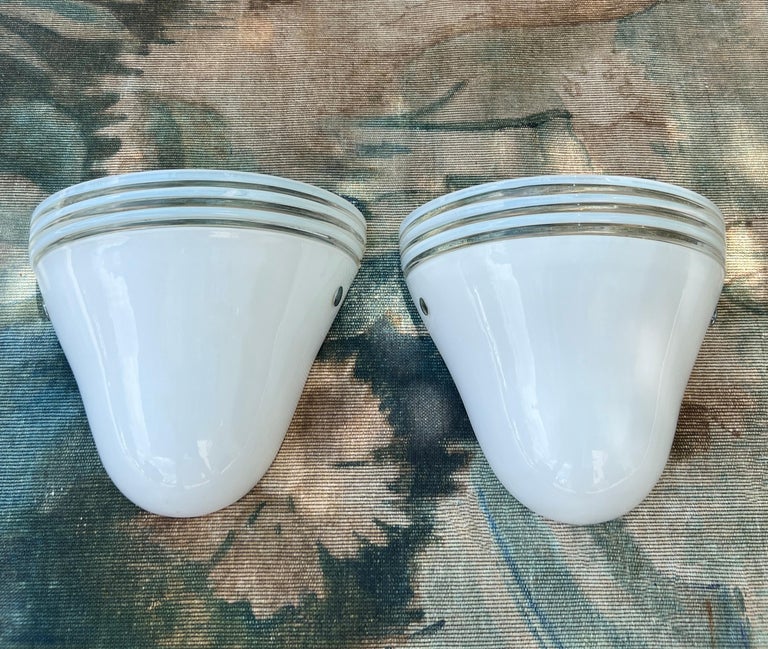 Mid-Century Modern sconces in white Murano glass designed by Roberto Pamio and Renato Toso for Leucos. The handblown sconces have diffuser shades in white glass and feature clear glass stripes along the top. Each sconce has two metal accents in