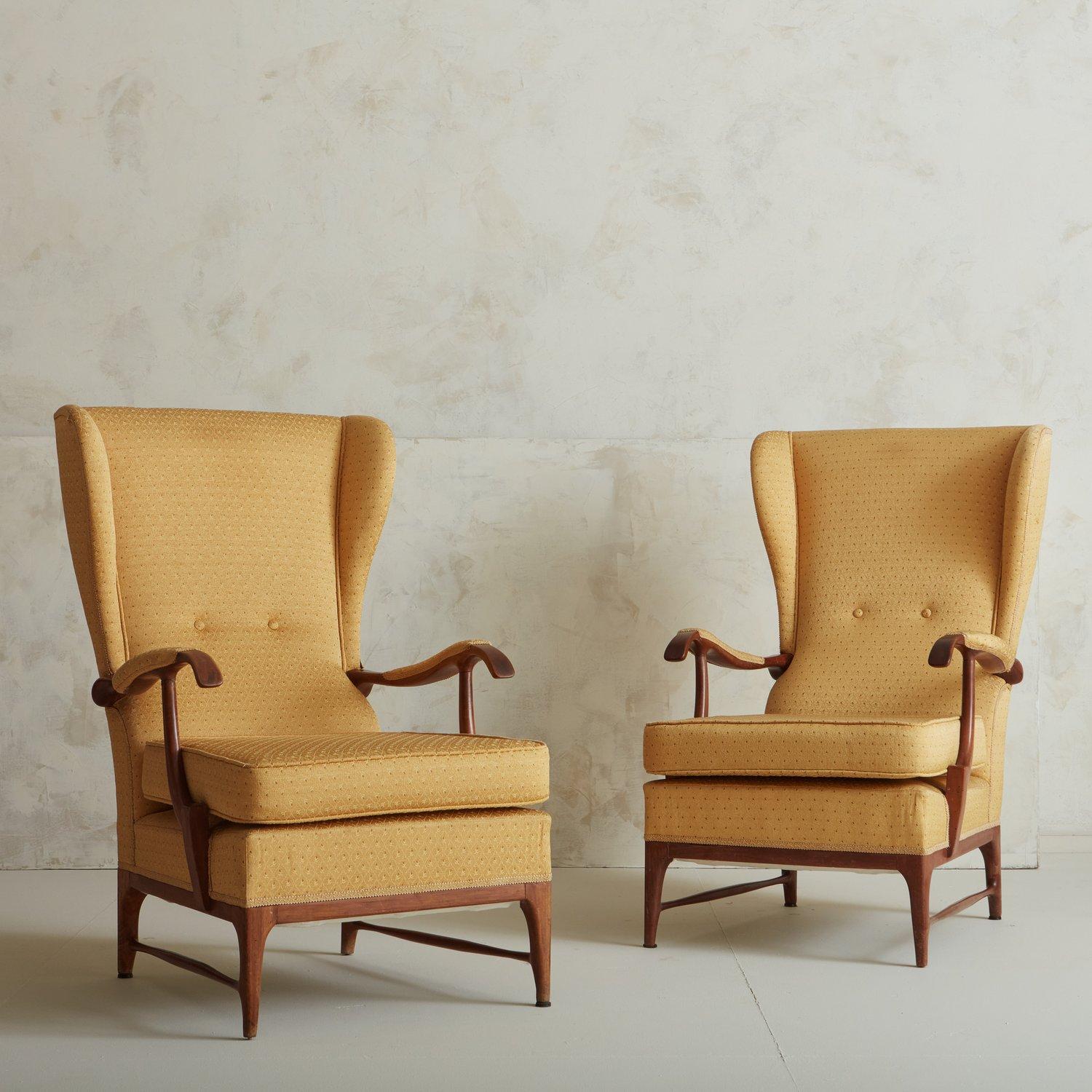 A handsome pair of vintage wingback lounge chairs in original yellow upholstery. These chairs feature wooden frames with stretchers on either side and dramatic tufted backs. Sourced in Italy, 20th century.