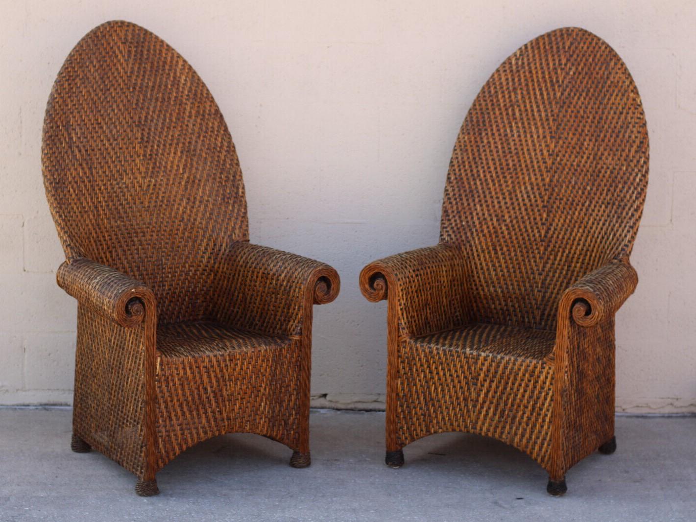 A pair of rolled-arm woven rattan armchairs with tall arched backs. The combination of light brown and dark brown wicker, with darker wicker feet, creates a beautiful contrast. These stunning rattan throne chairs are in good vintage as-found