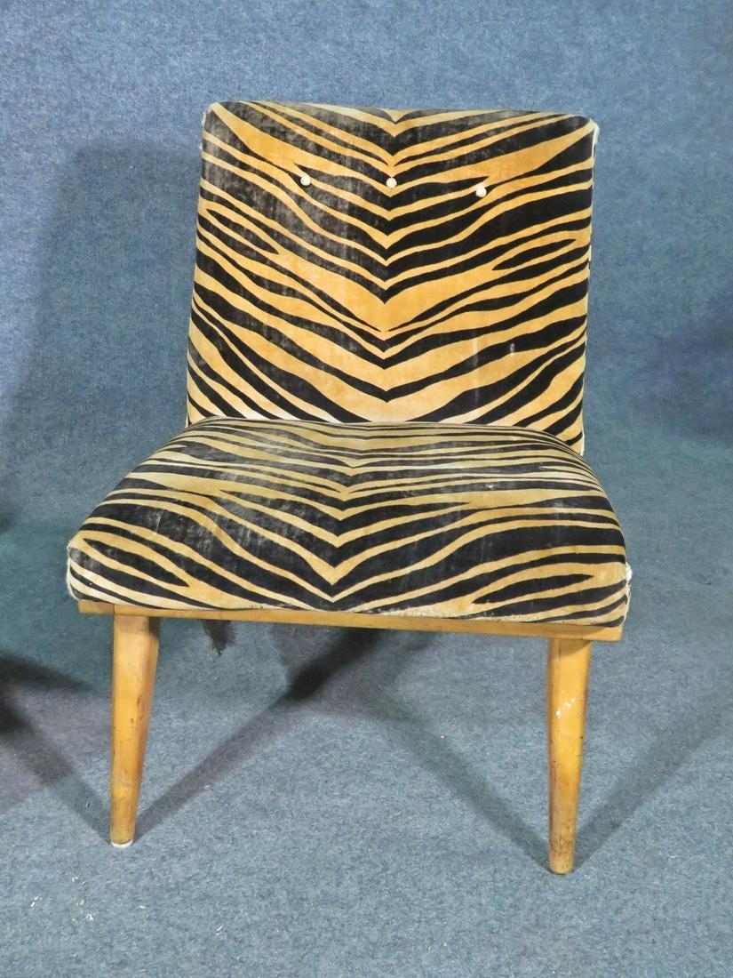 This vintage pair of lounge chairs, upholstered in a vibrant zebra print fabric, are just as comfortable as they are stylish. Sure to make a bold statement in any setting, these chairs are crafted with Mid-Century quality. Please confirm item