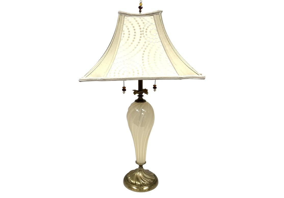 Paire de lampes de table Virginia en verre soufflé opaque de couleur crème, doubles douilles et abat-jour rectangulaire recouvert de dupioni à pois crème avec panneaux d'angle en soie beige unie. La lampe est munie de tirettes en verre perlé et d'un