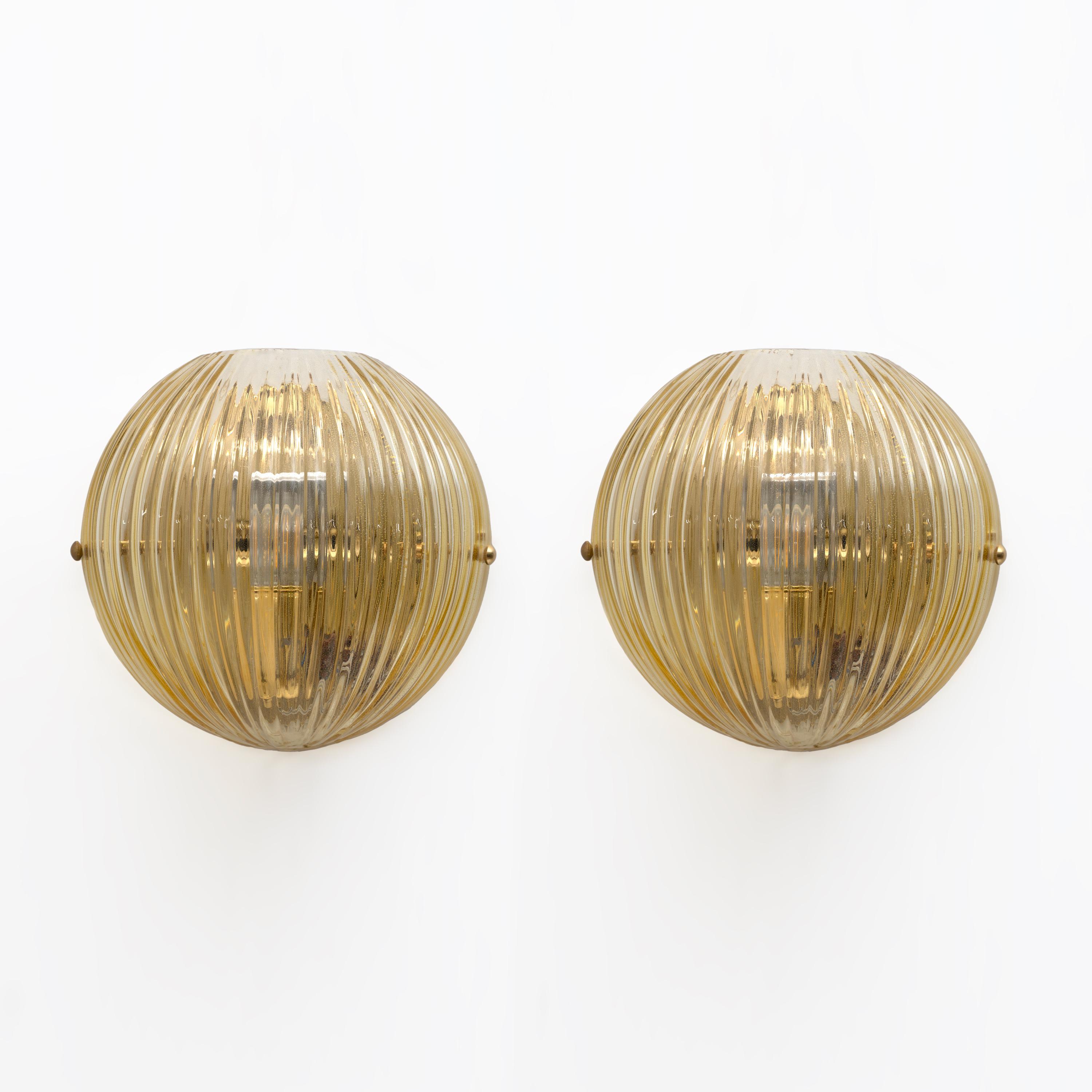 Pair of Vistosi wall lamps in blown Murano glass with gold dust. Each lamp holder has an E26 fitting for the United States or E27 for Europe. Several pairs available, ask for availability. The lamp holder is printed with the symbol of the famous