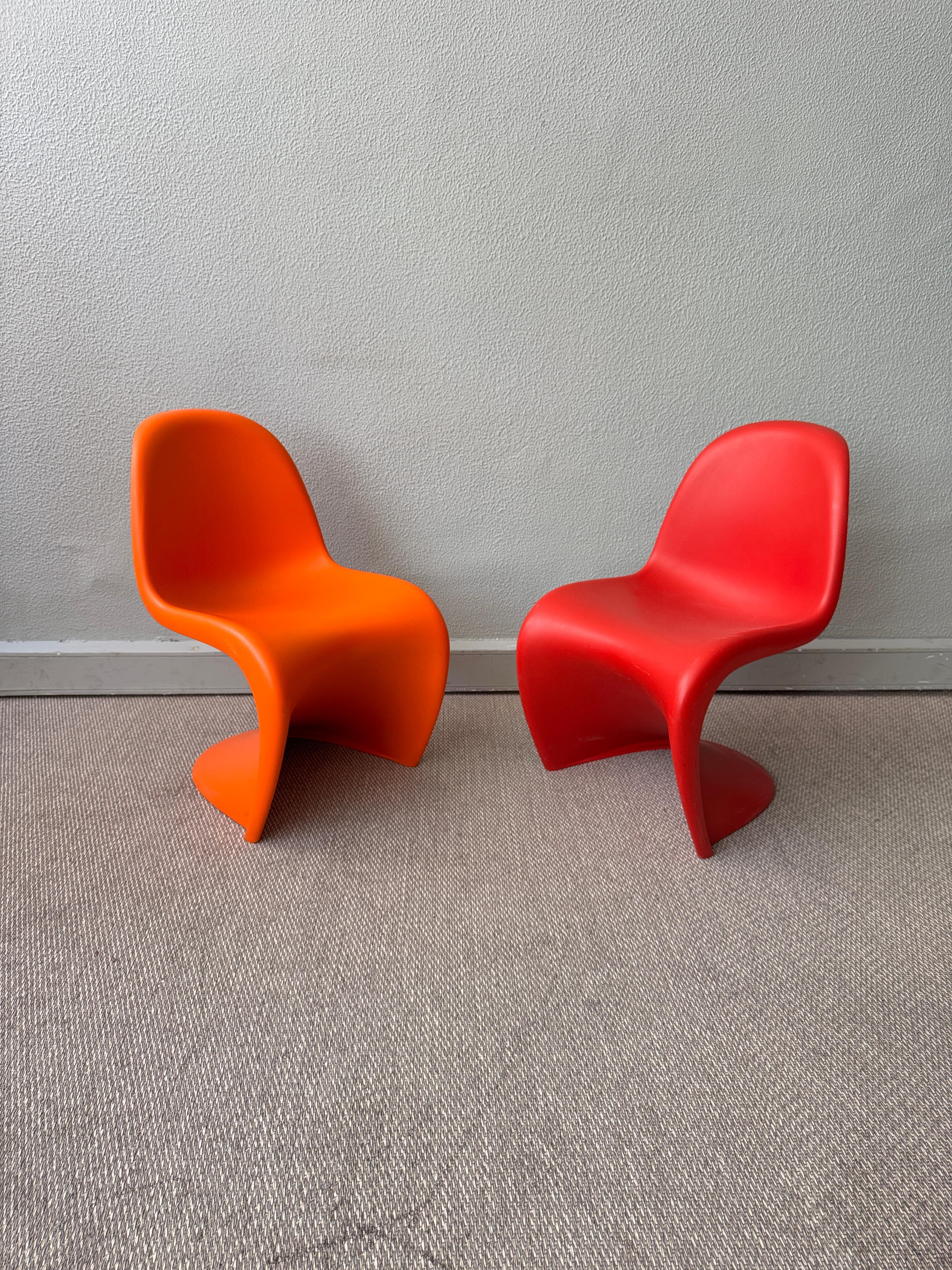Coppia di sedie Verner Panton S Junior di Vitra, prodotte nel 2005 (rosso) e nel 2009 (arancione). Queste sedute giocose reinterpretano uno degli arredi più iconici del XX secolo. Originariamente concepita negli anni '60, la Panton Chair è stata la