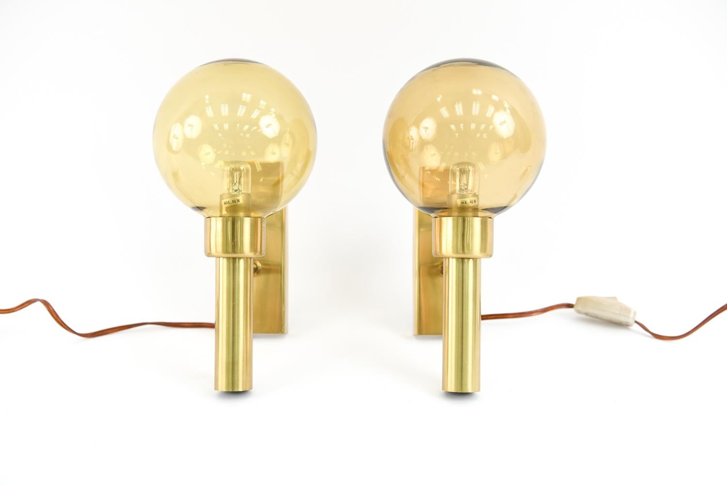 This pair of Bodega model sconces by Vitrika are in the style of iconic lighting designer Hans Agne Jakobsson. These Danish midcentury sconces feature brass frames with yellow glass globe shades.