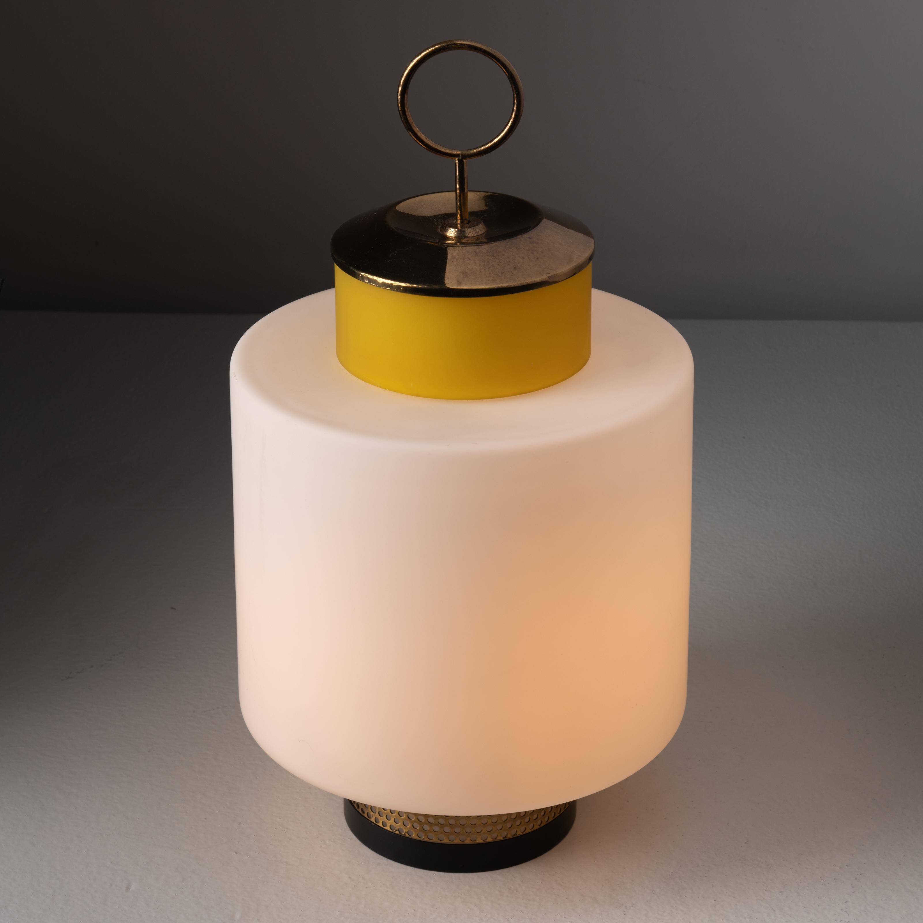 Pair of table lamps by Stilnovo. Manufactured in Italy, circa 1950s. Lantern style lamps consist of opal glass main diffusers with yellow colored accent glass above. Perforated aged brass bottom housing and a brass loop on top for an added feature.