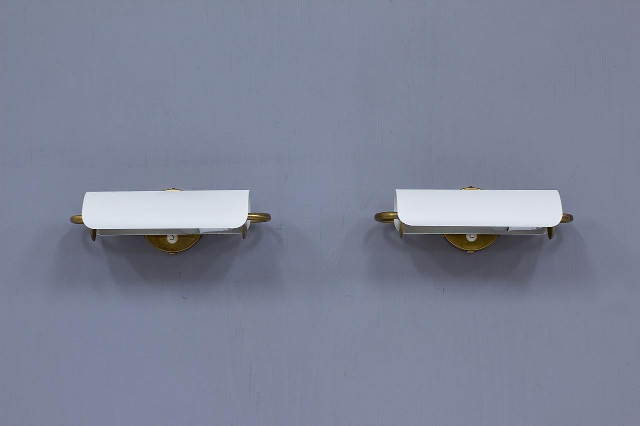 Elegant pair of brass and metal wall lamps model 4131 manufactured by NK, Nordiska Kompaniet. The design is attributed to Bertil Brisborg which was the chief architect at the Lighting department of NK for more than 30 years. 
Manufactured in Sweden