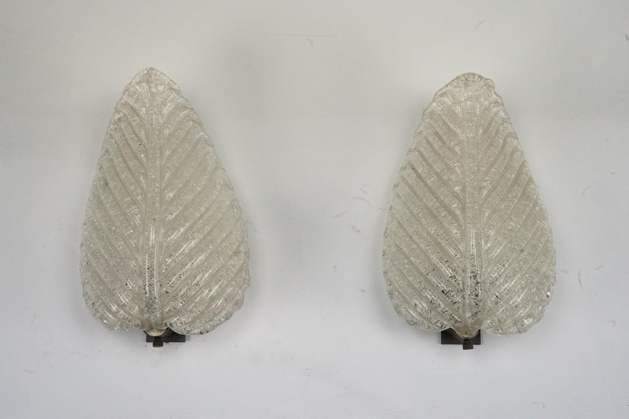 Pareja de lámparas de pared diseñadas por Ercole Barovier, realizadas en cristal de Murano Rugiadoso, Italia, años 50. Estas exquisitas lámparas vintage presentan pantallas de cristal en forma de hoja con un patrón texturizado, mostrando el
