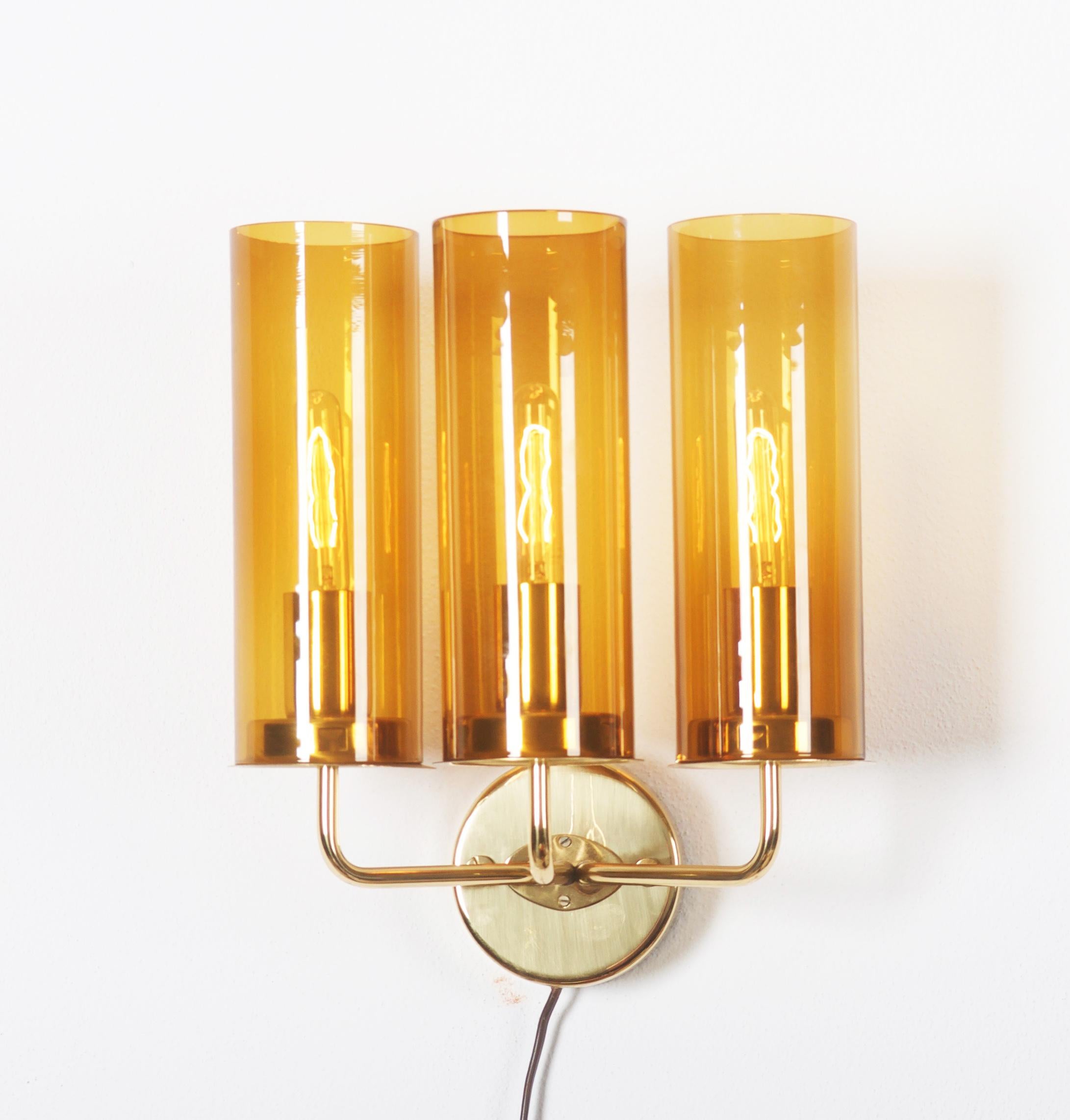 Modernist wall lamp in brass and amber-colored glass.
Model V 169/3. Designed and made in Sweden by Hans-Agne Jakobsson from, circa 1960 second half.
Fully working and in very good vintage condition. 
A pair available.