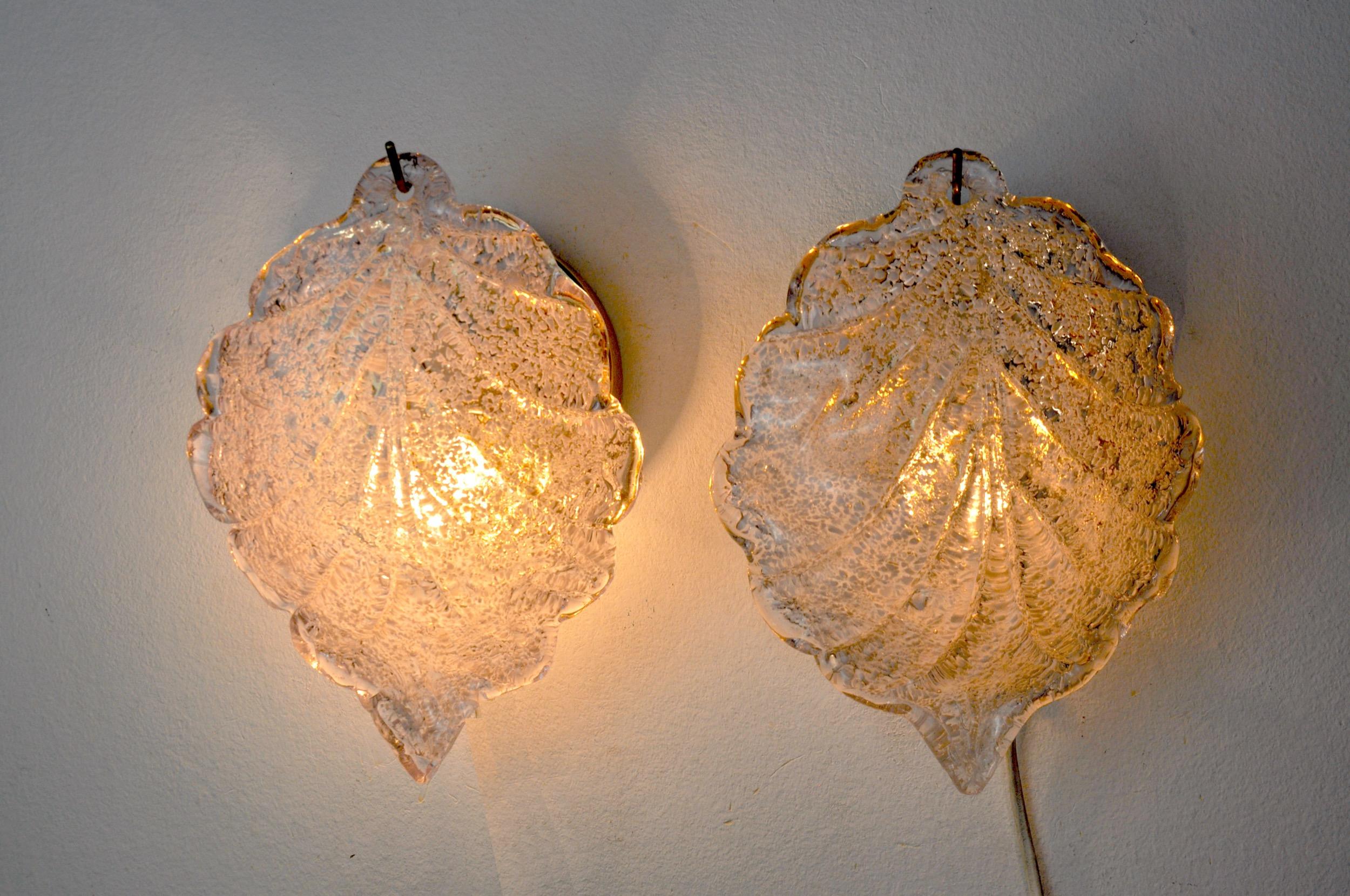 Very nice pair of floral sconces mazzega designated and produced in Murano, Italy in the 70s.
This pair of sconces is composed of a sheet of white frosted Murano glass, suspended from a gilded metal structure.
Rare design object that will illuminate