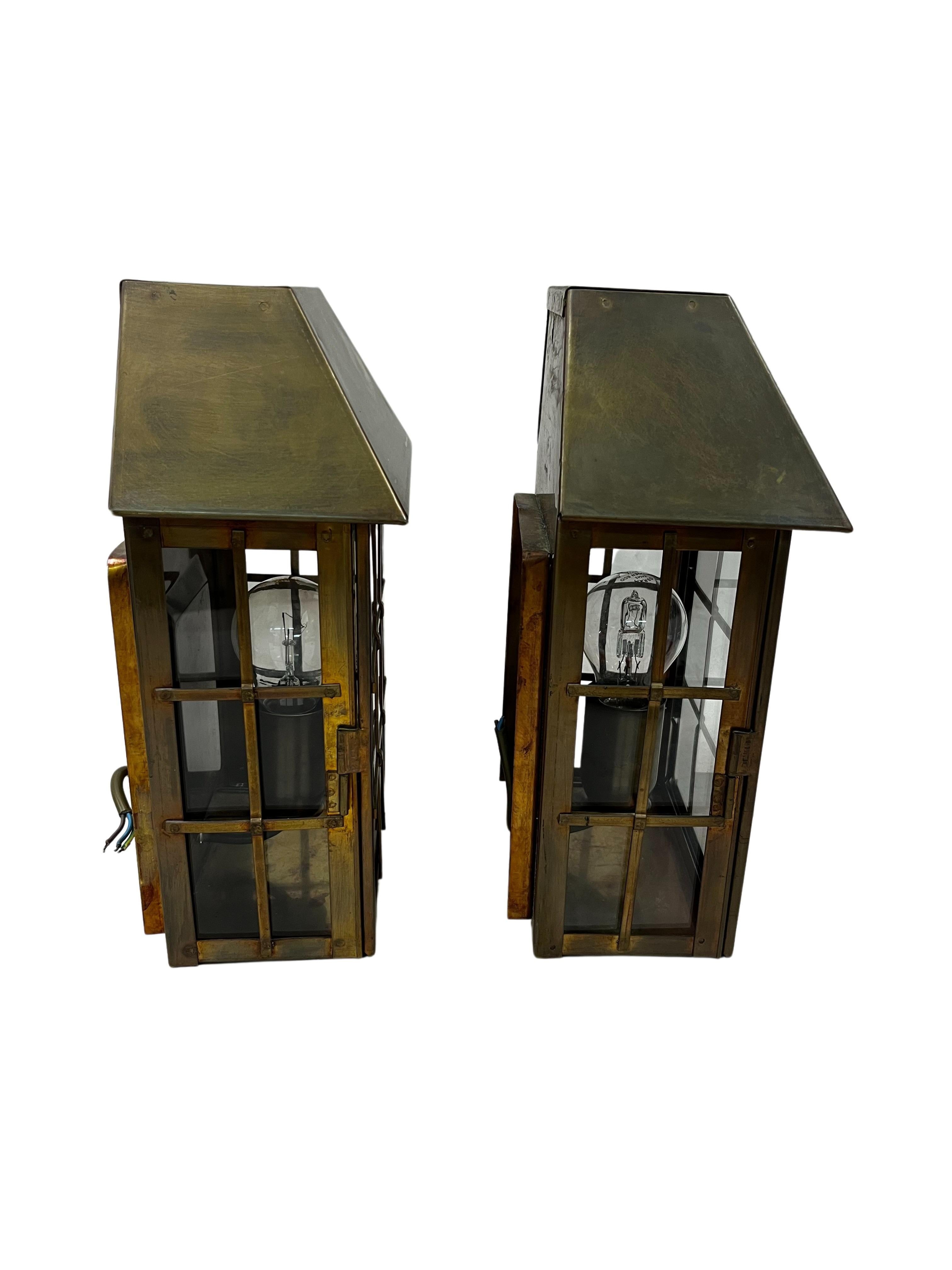 Beautiful special wall lamps with an architectural design, made entirely of brass that has been patinated. Manufactured - probably in Italy, in the 1950s.

The two wall lamps are made like small houses, with roofs and a stylized opening window. The