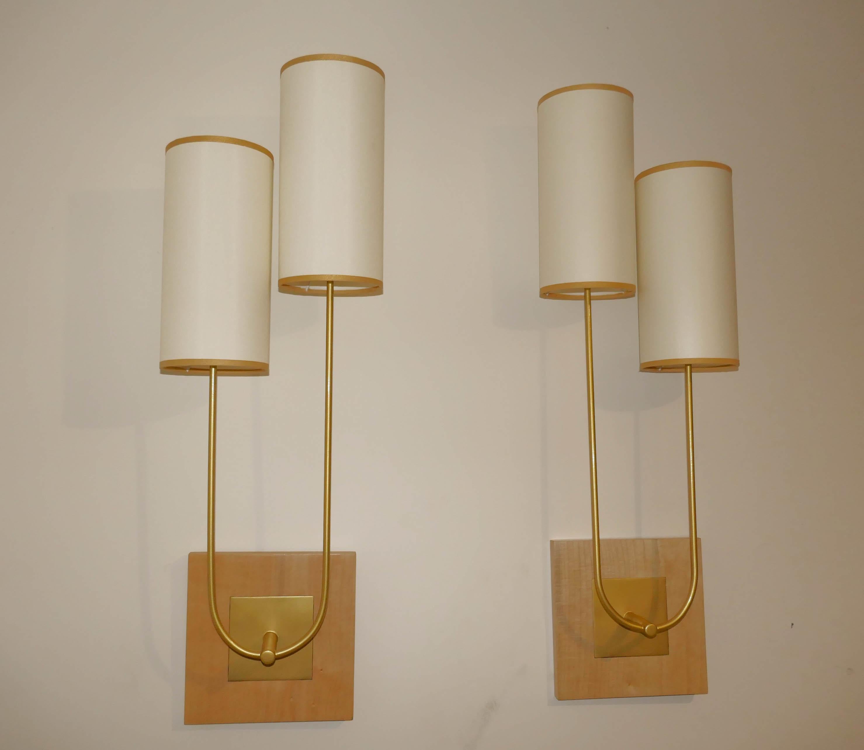 Paar Wandleuchten aus Metall mit Goldpatina mit Sycomore-Holzplatte. Die Lampenschirme sind aus Seidenstoff mit goldener Borte. Die Wandlampen können mit einem Adapter, der mit den Lampen mitgeliefert wird, mit e27 und b22 Leuchtmitteln bestückt
