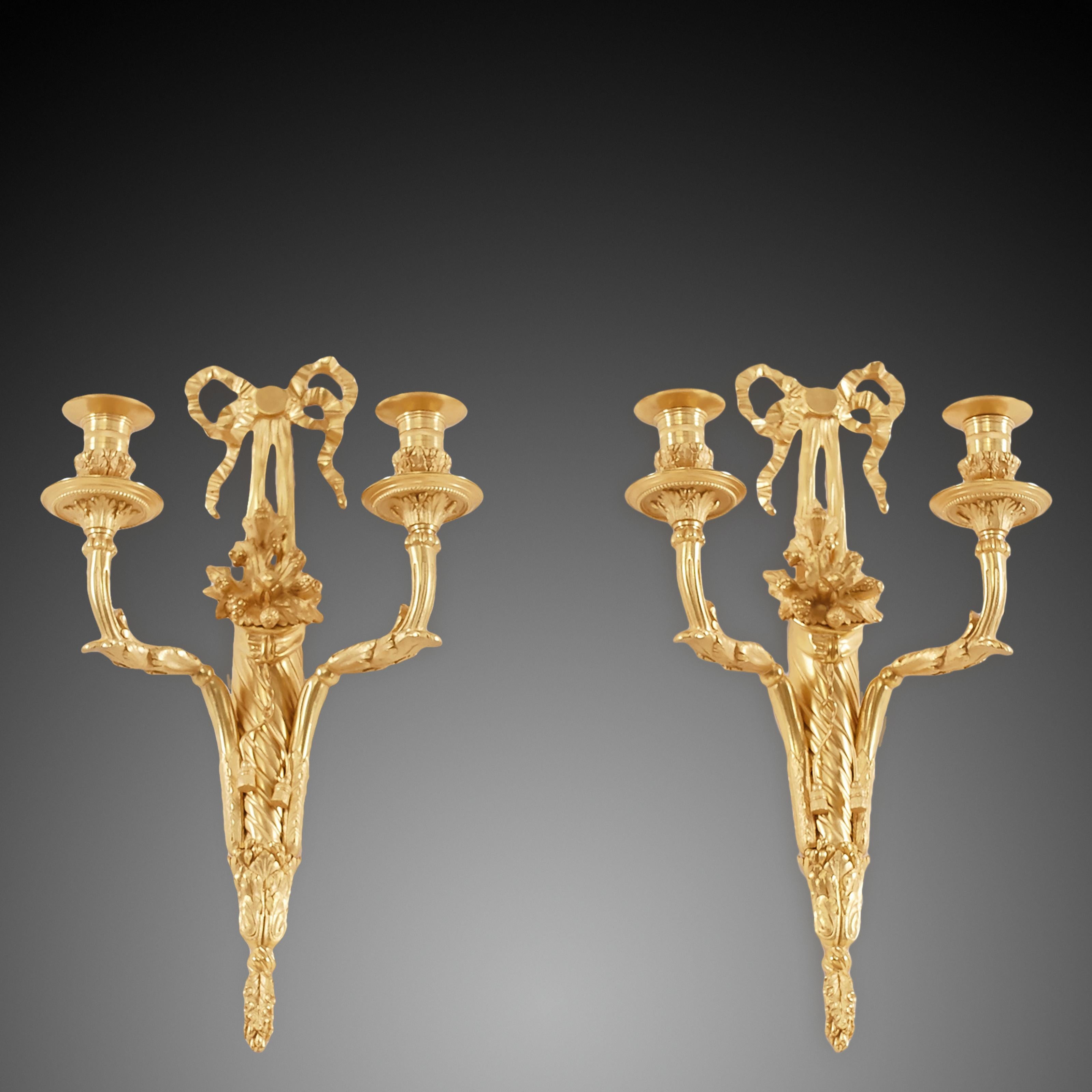 Pair of candle sconces with two cornucopia styled arms made from ormolu, handcrafted by master craftsmen in the 19th century..The pair of antique wall sconces have a distinct French Louis XVI style, which shows flexibility with the characteristic