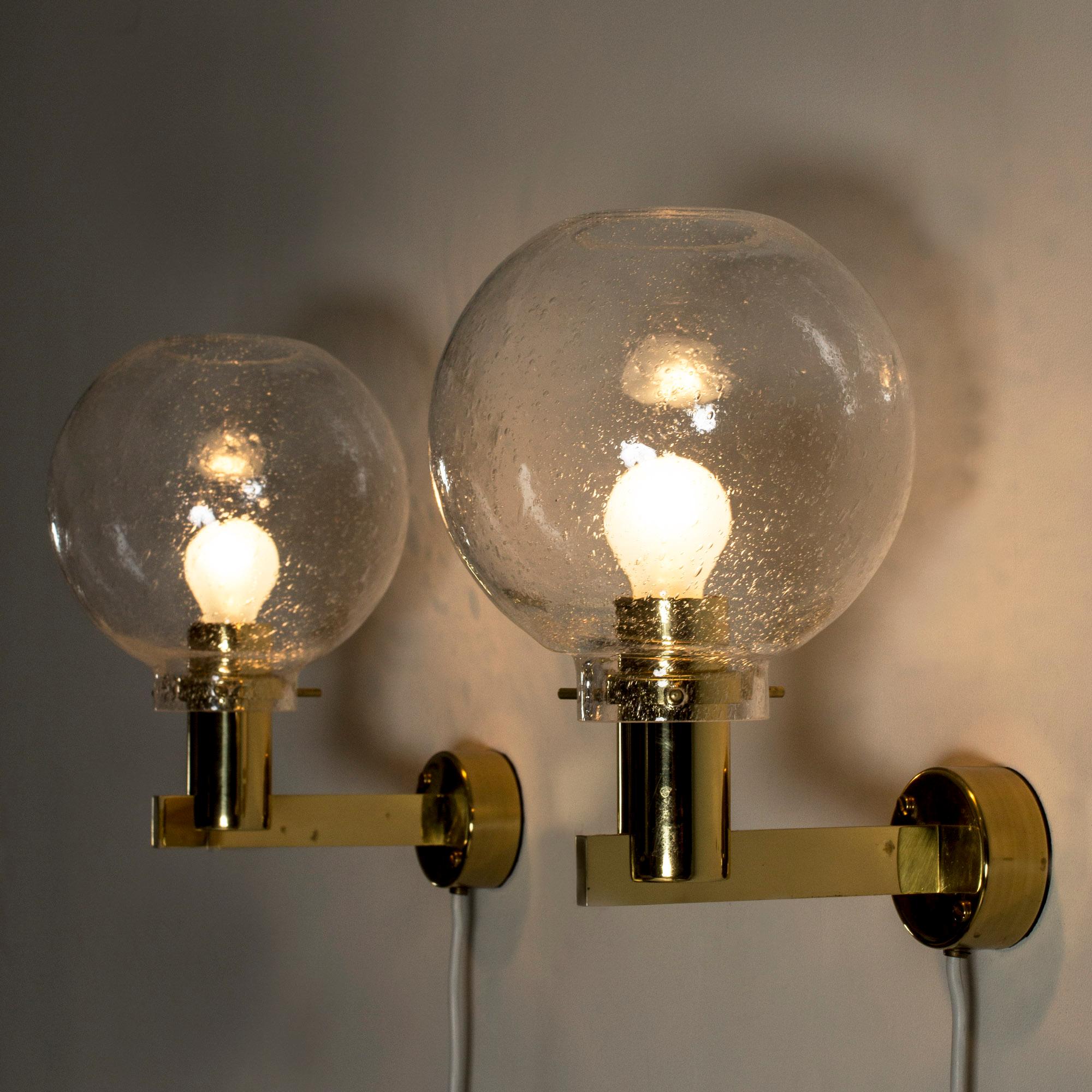 Pair of wall lamps by Hans-Agne Jakobsson, with brass frames and large glass shades. The angular brass forms contrasts nicely with the clear glass with air bubbles caught inside.