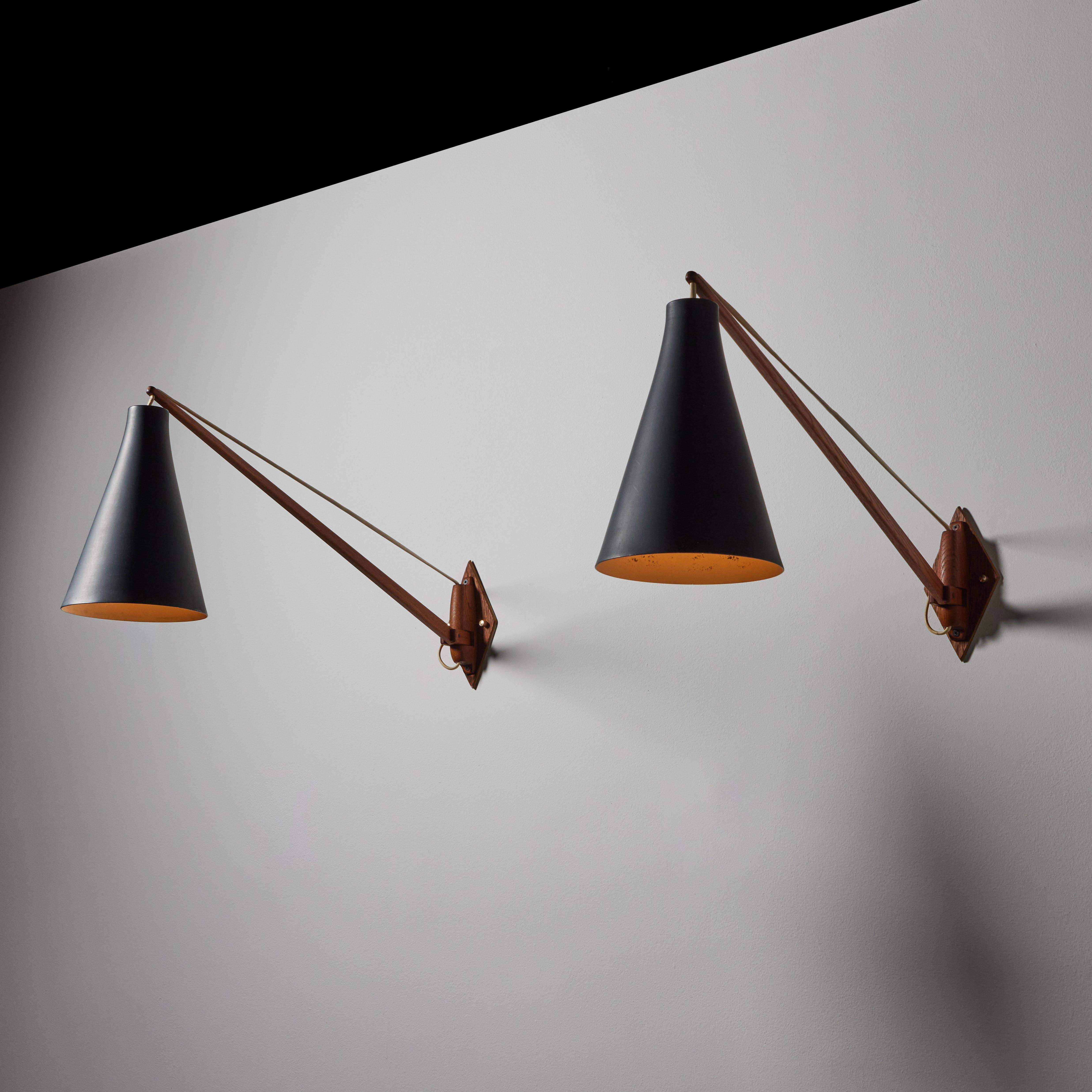 Pair of wall lights by Uno and Östen Kristiansson for Luxus. Designed and manufactured in Sweden, circa 1950's. Enameled metal, teak wood. Rewired for U.S. standards. adjustable shades. We recommend two E14 60w maximum bulbs per fixture. Bulbs not
