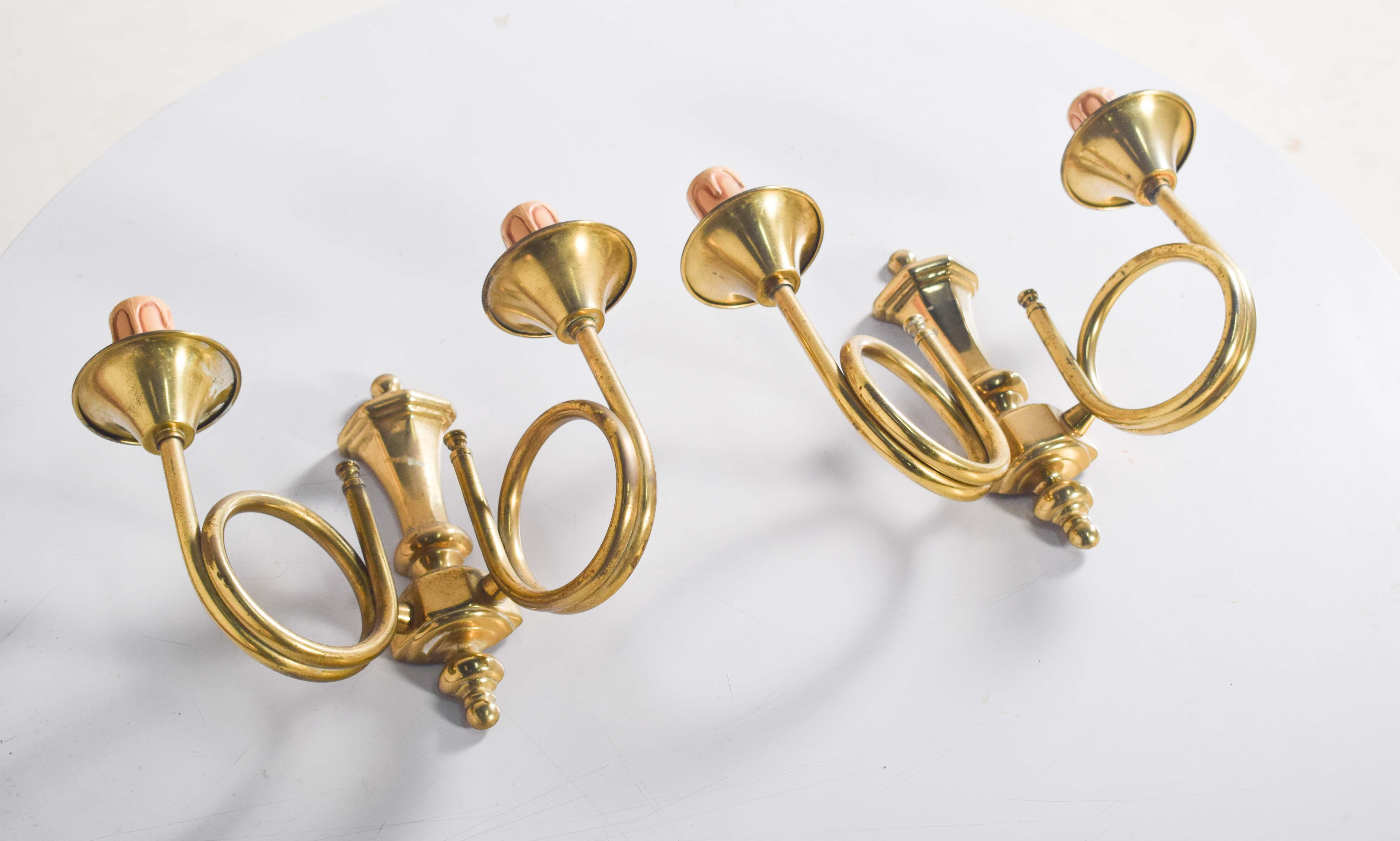 Questa coppia di applique in ottone emana un fascino raffinato e vintage, grazie ai due bracci graziosamente curvati. I bracci a tromba emergono con eleganza da un corpo centrale con dettagli geometrici, aggiungendo equilibrio architettonico e