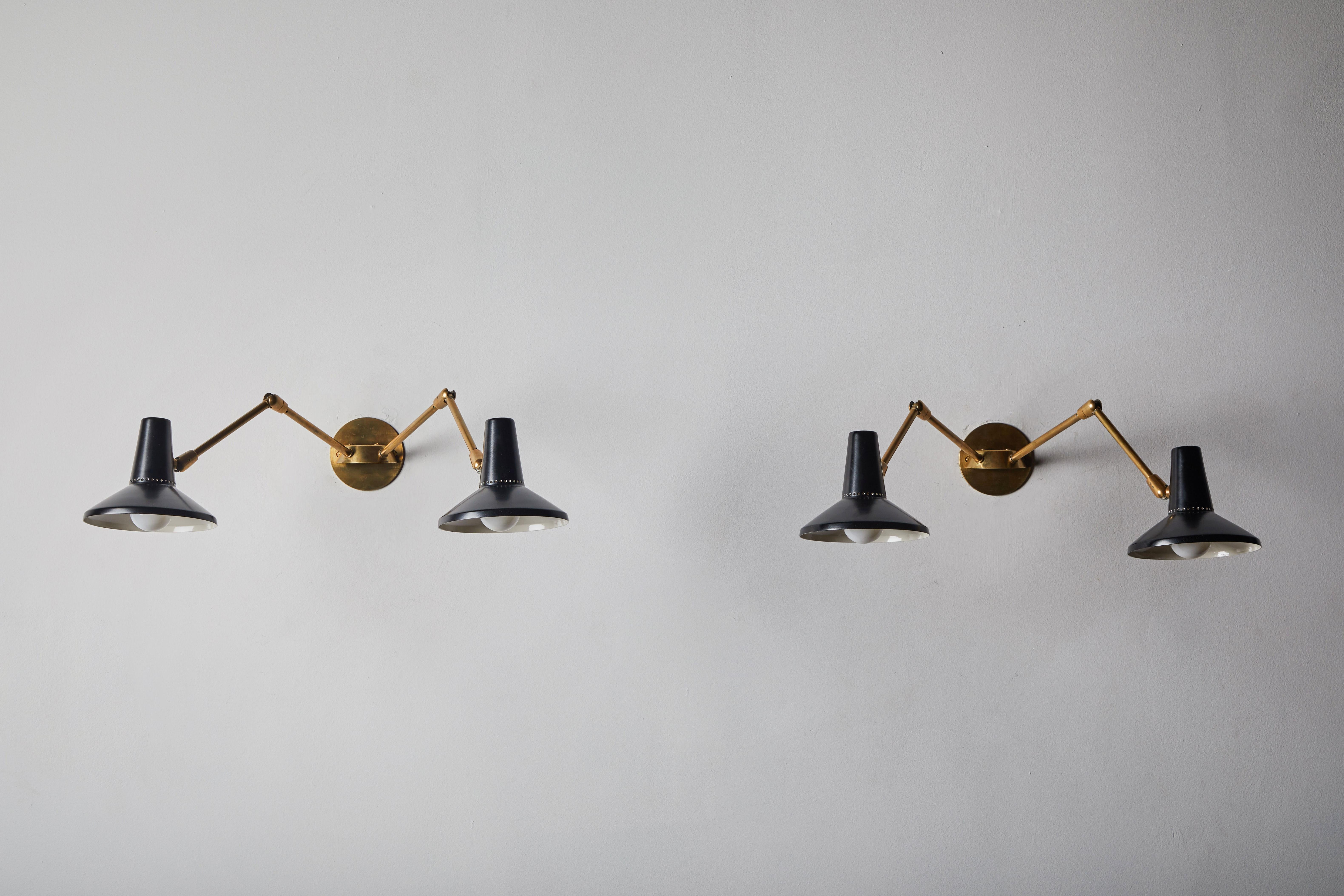 Pair of wall lights in the style of Giuseppe Ostuni for O-Luce. Designed and manufactured in Italy, circa 1950s. Enameled metal and brass. Rewired for US junction boxes. Custom brass backplates. Arms and shades articulate to various positions. Each