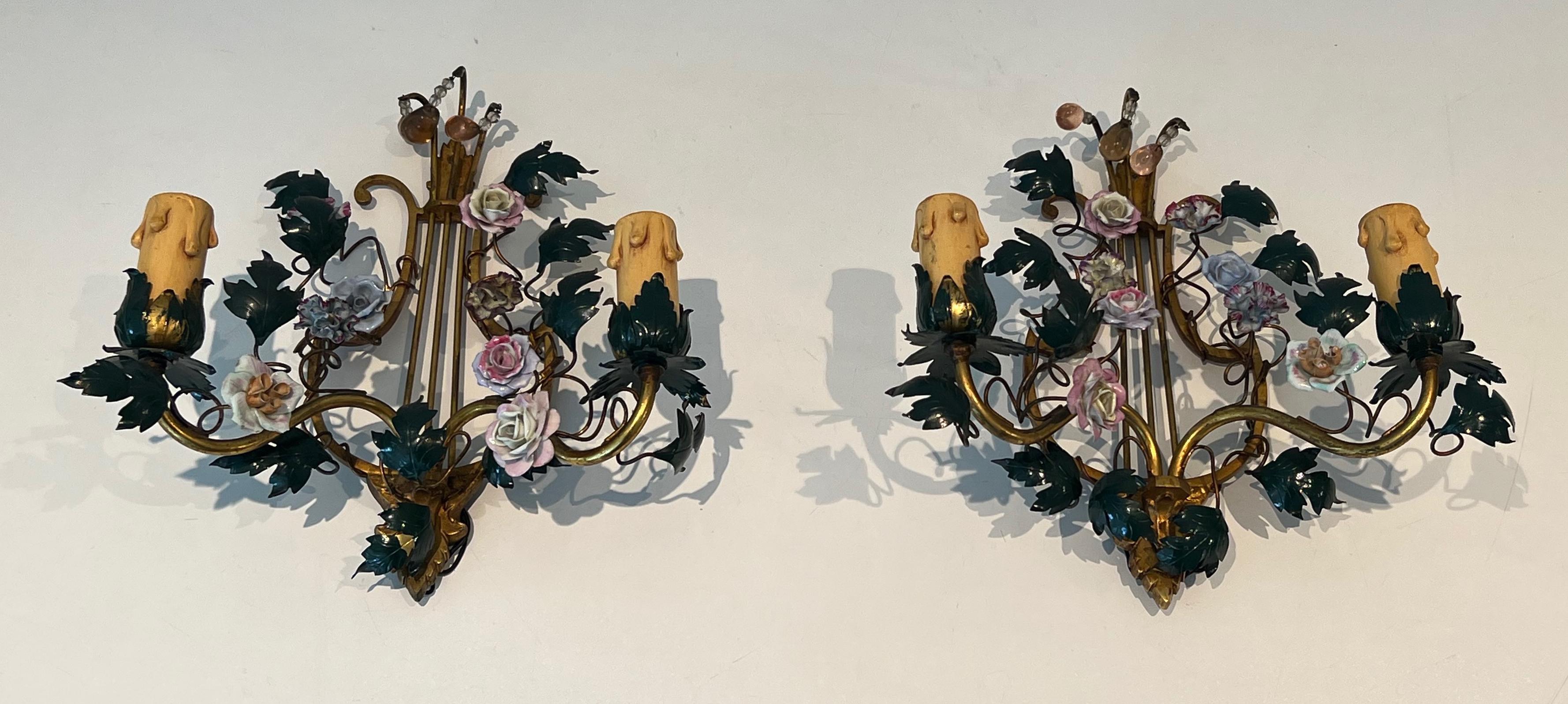 Cette paire d'appliques est en bronze et métal patiné avec des fleurs en porcelaine. Il s'agit d'un ouvrage français. Circa 1940