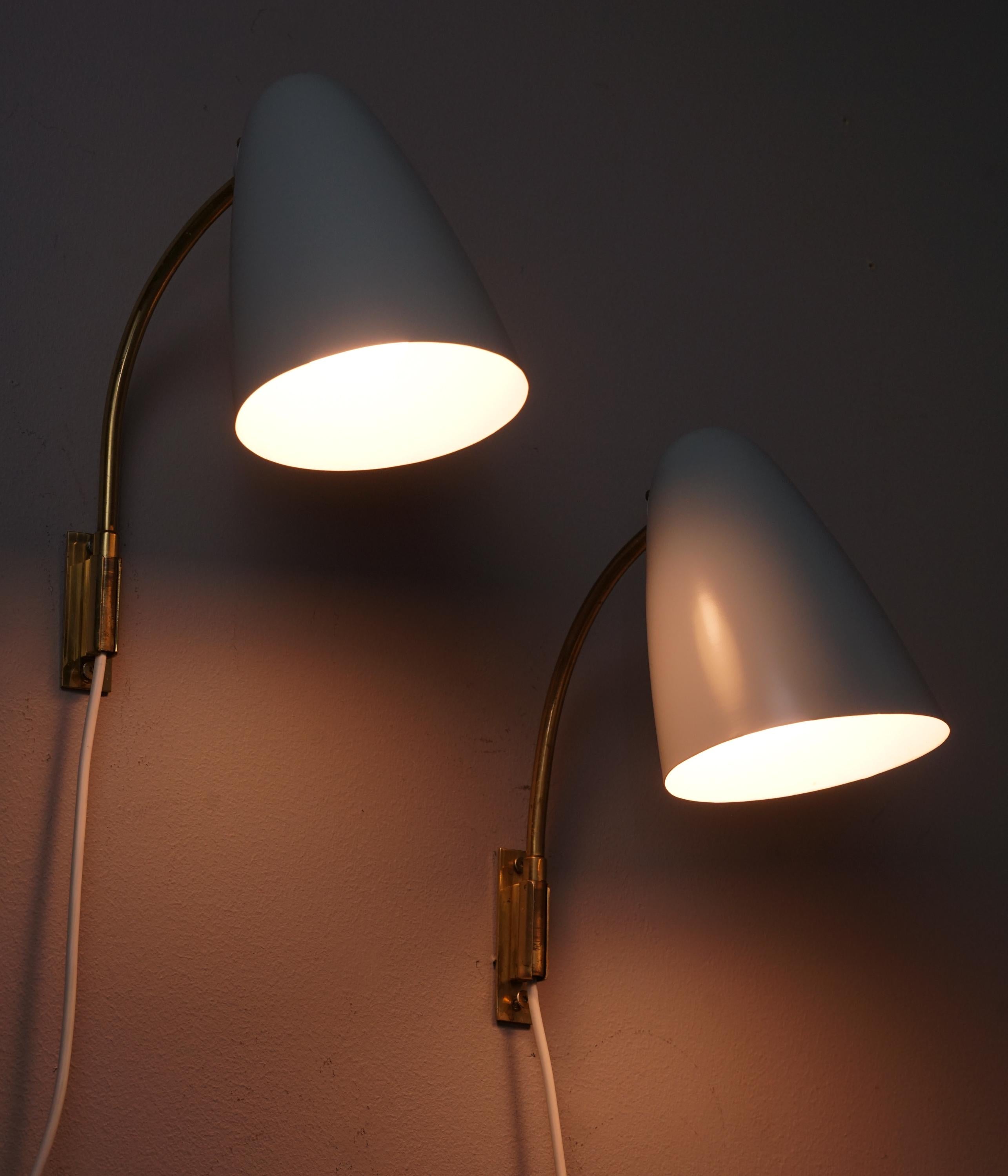 Pair of wall lights model 3054, designed by Lisa Johansson-Pape, manufactured by Stockmann-Orno, 1950s. Marked. Brass frame with painted metal shade. Good vintage condition, minor patina and wear consistent with age and use. The wall lights are sold