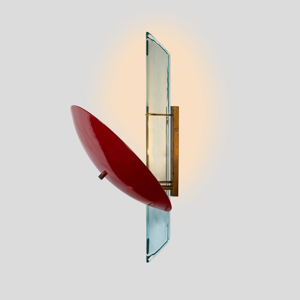 An elegant pair of wall lights. Red enamelled metal shade shaped in a concave circular form with cut clear thick glass detail on a brass structure.
A 2009 Italian design by Roberto Rida.
This pair would look stunning in any kind of interior settings