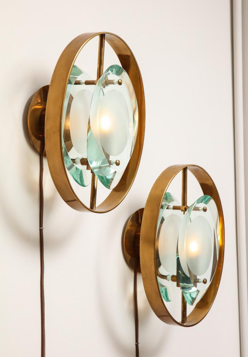 Pair of Wall Sconces, #2240 by Max Ingrand for Fontana Arte.  Crystal-cut glass, brass. Each sconce features 2 glass lenses on either side of a single candelabra socket with brass mounts and surround. Overall wear and oxidation to brass. Wiring and