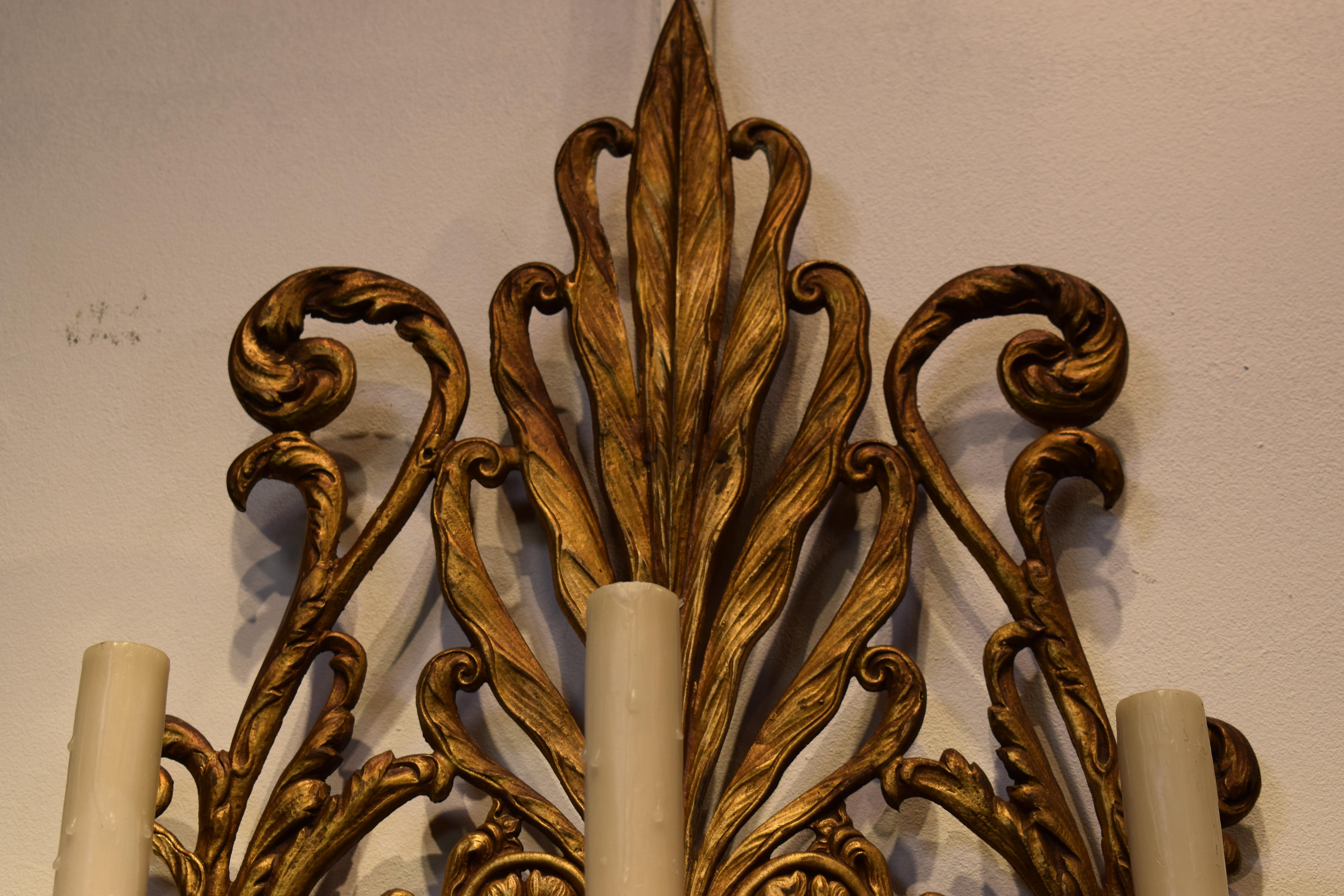 Paire d'appliques murales en bronze et cristal, chacune ayant une plaque arrière en forme d'anthemion, une couronne de demi-lumière avec trois lumières au-dessus d'une bande de prismes carrés et en forme de cerf-volant, et une doublure en acier. 