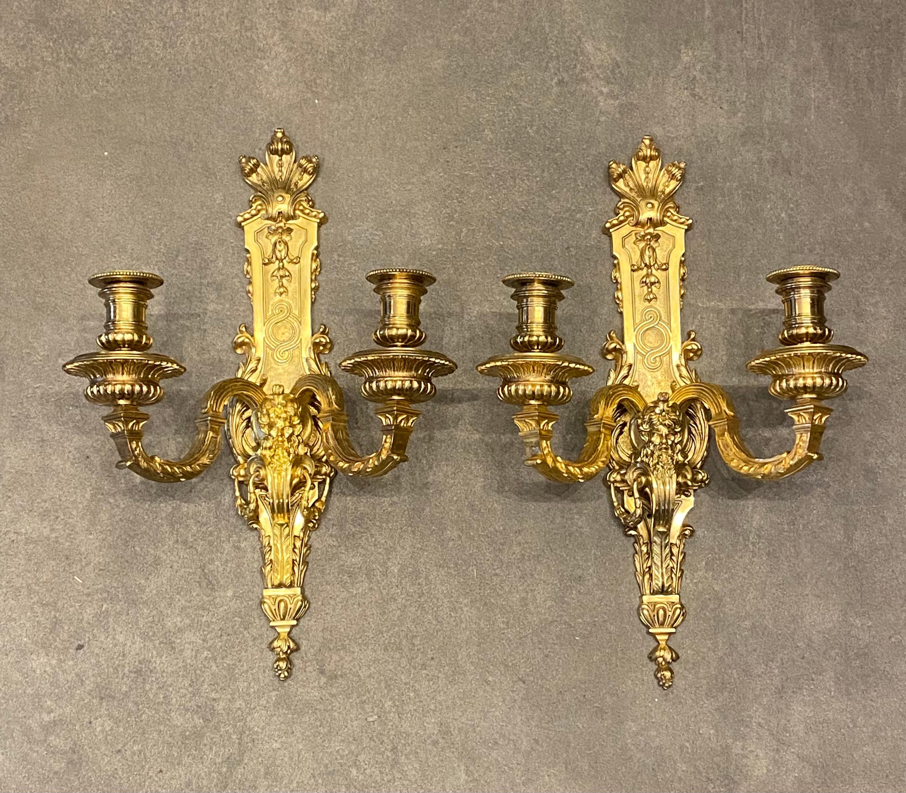 Pair of gilded bronze sconces with two lights. The central stem is decorated with a mascaron in the middle of the two branches. All richly carved with palmettes, garlands and other friezes Stamped and dated on the back: G 1860 
France, 19th century