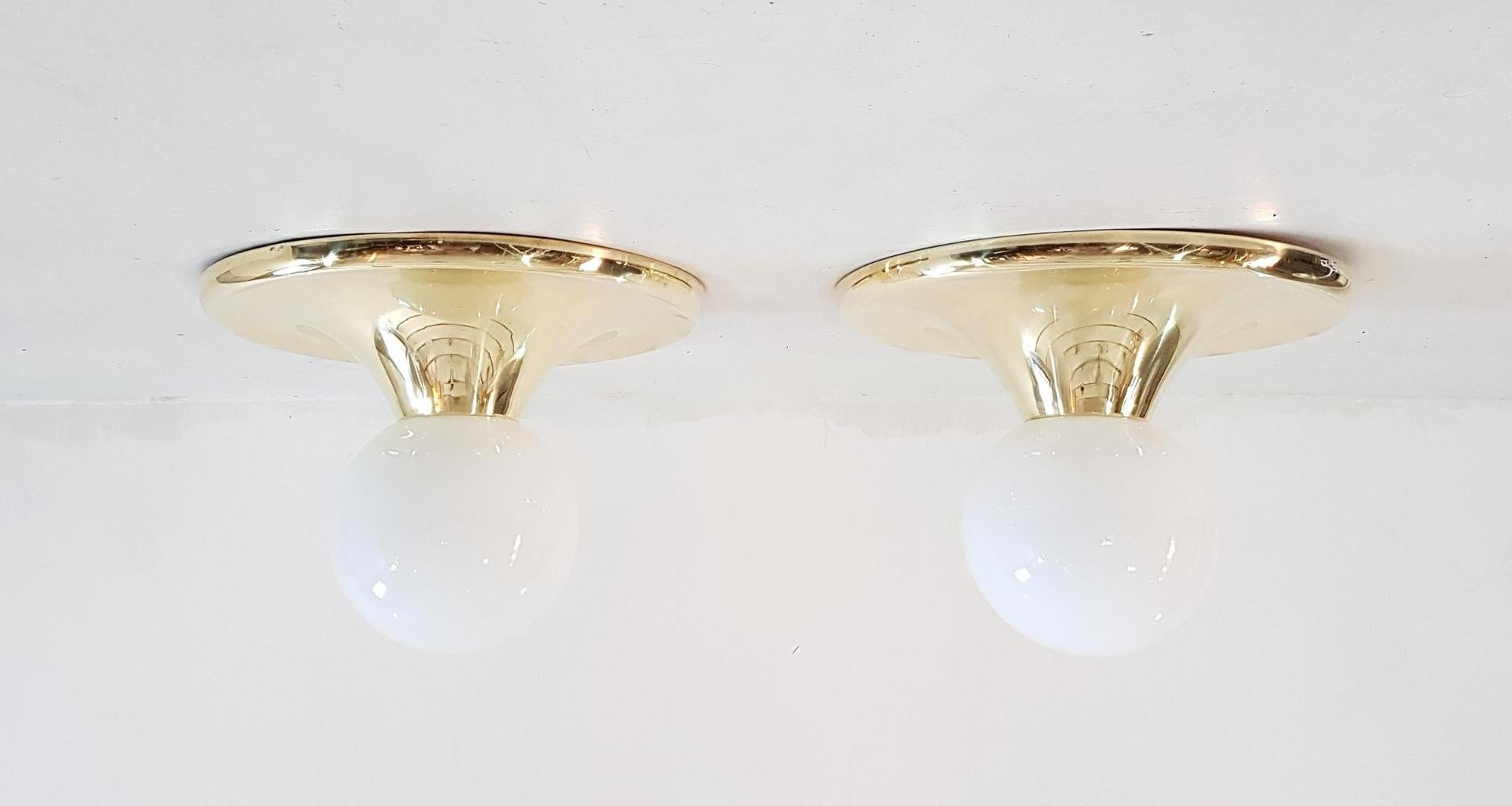 A large pair of lamps that can be used as flushmounts or wall sconces by Achille & Pier Giacomo Castiglioni for Flos. Designed and manufactured in Italy, 1965. Brass and opaline glass. Each light takes one E27 bulb. The brass has been professionally