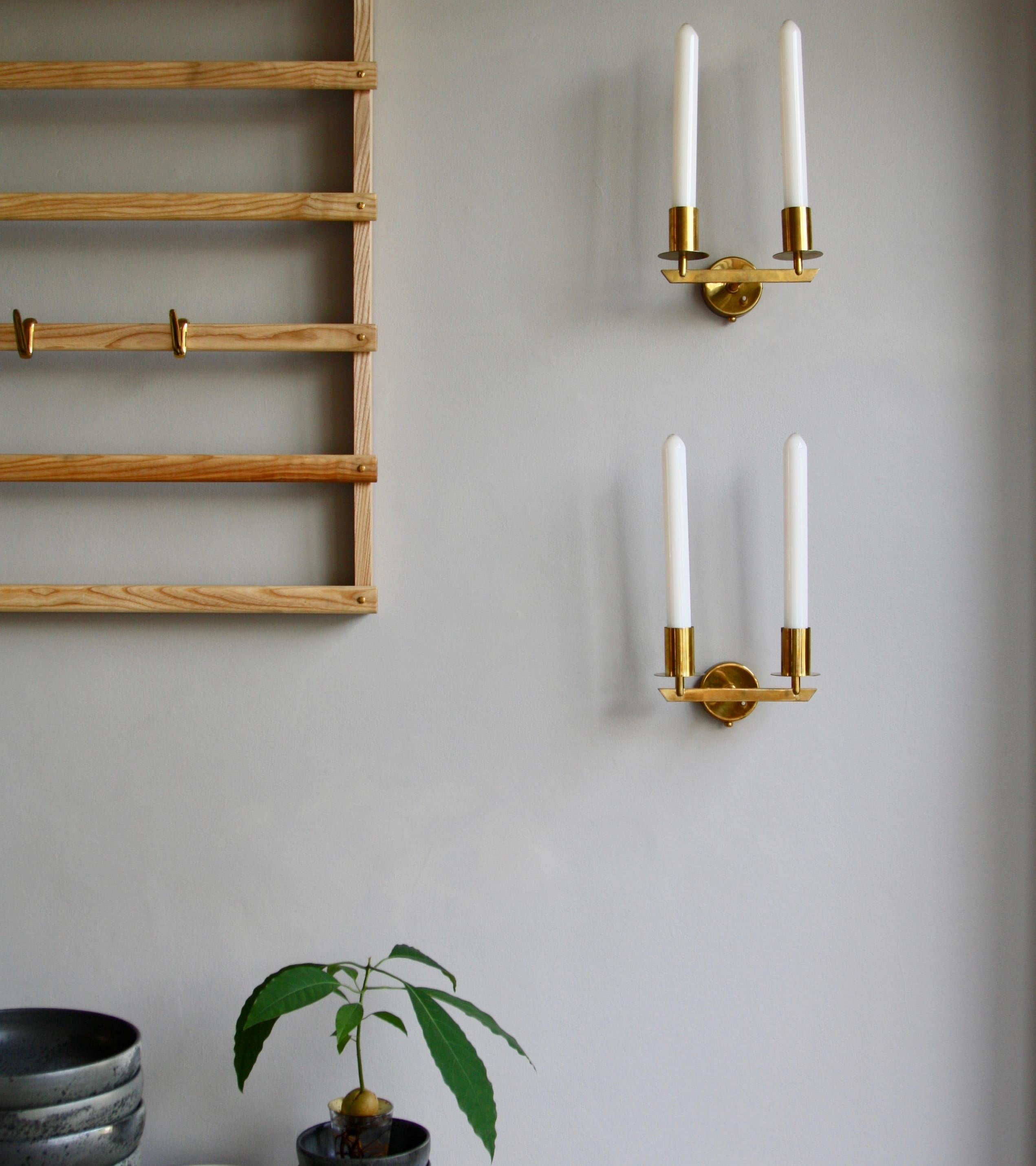 A pair of wall sconces in brass designed and made by Itsu Oy, Finland, circa 1950. The form of the lights’ is entirely made up of geometric shapes; circles, cylinders and a trapezium. Accentuating the visibility of these shapes are the oversized