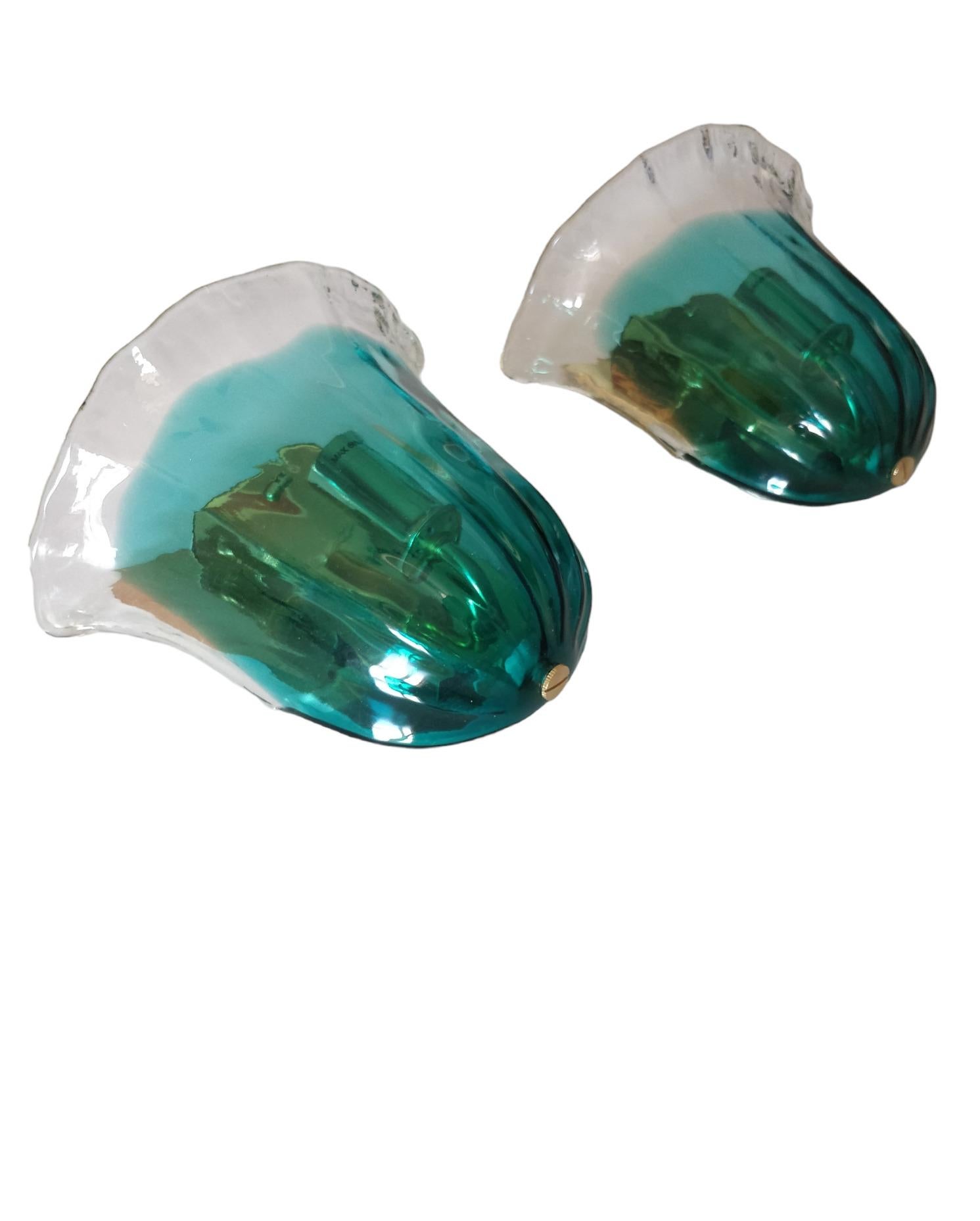 The design of these wall sconces is elegance and refinement, with the glass shaped like a flower that delicately blends green and transparent glass elements to create a captivating visual effect when the light shines through. The glass with a green