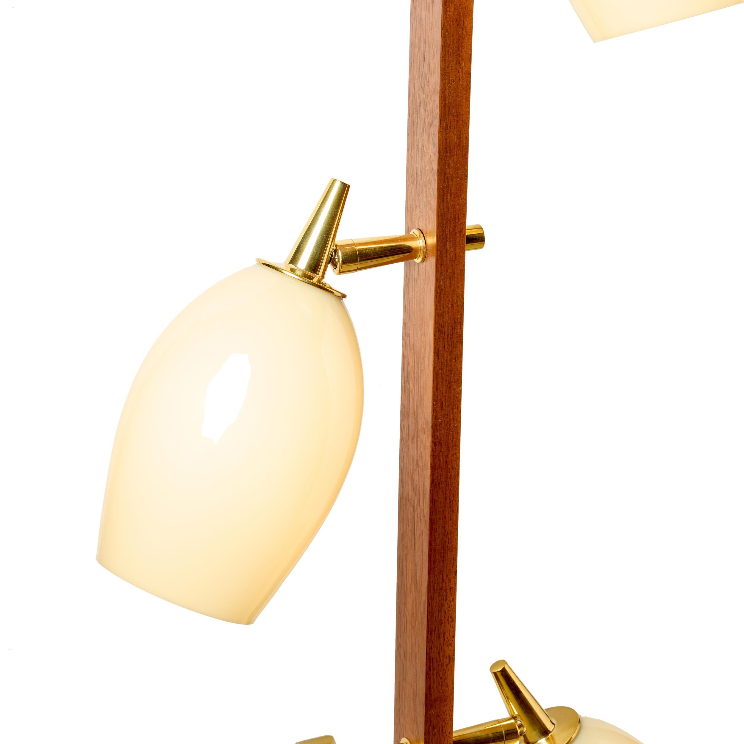 A pair of walnut and brass wall sconces, each with 3 articulating cream colored glass shades. Verticals are tapered at beth ends. Machined and polished brass wall stand-off. Electric can either be hard-wired or plugged-in.