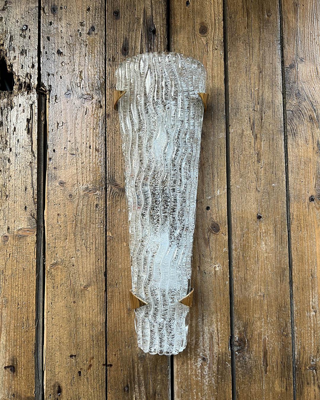 Elegant and sculptural wall sconces composed of thick, textured glass panels with a wave-like pattern, mounted on refined brass brackets. Designed by Maison ARLUS in the 1960s, these pieces are a quintessential example of French mid-century