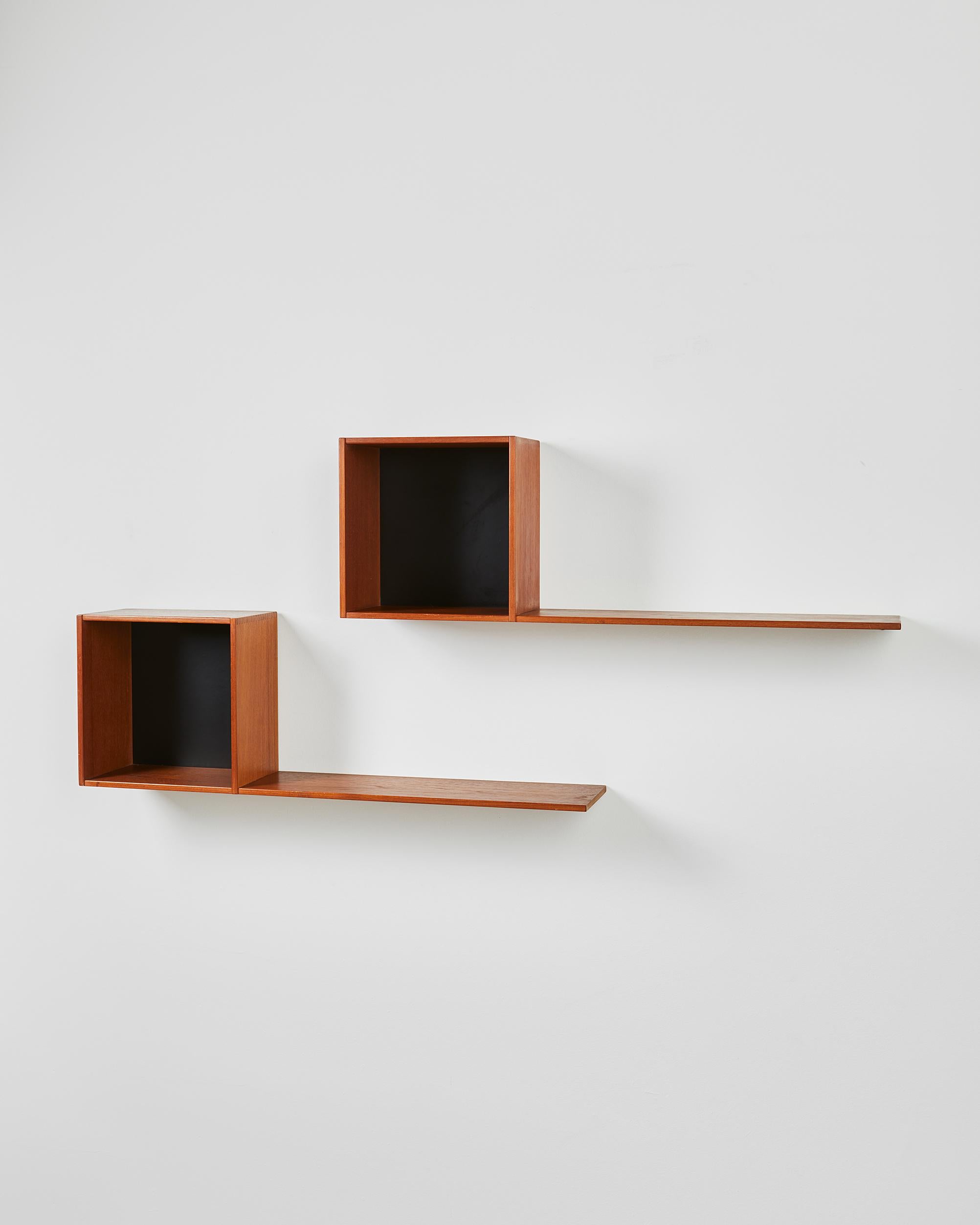 This pair of wall-mounted shelves, produced in Sweden during the 1950s, offers a refined balance of form and function. Each unit features a rectilinear open cube paired with an extended horizontal shelf, forming a visually striking composition. The