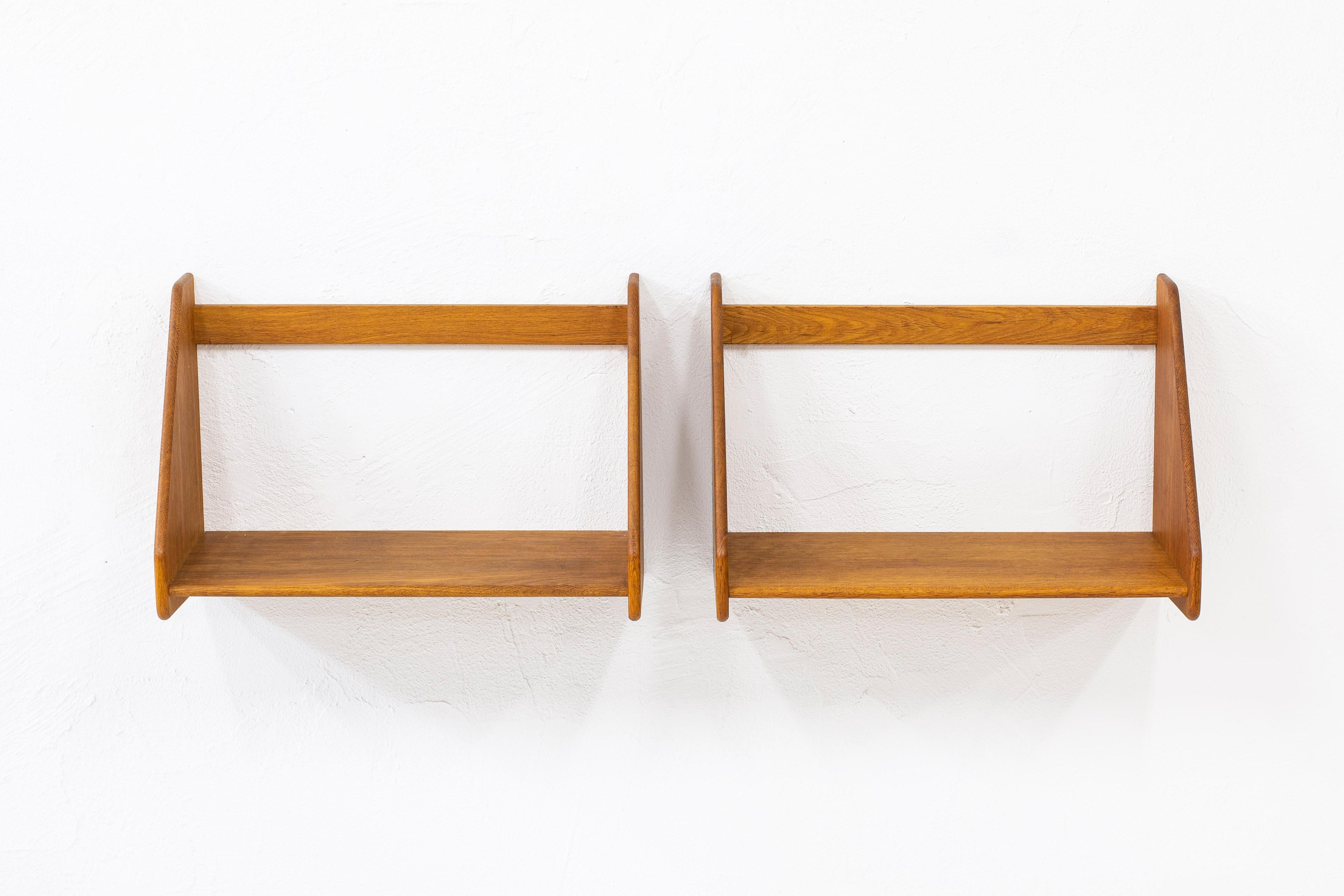 Wall shelves designed by Hans J. Wegner. Produced in Denmark by RY Møbler during the 1960s. Made from solid oak. Excellent vintage condition with very few signs of wear and use. Comes with four brass hooks for hanging on the wall. Both shelves