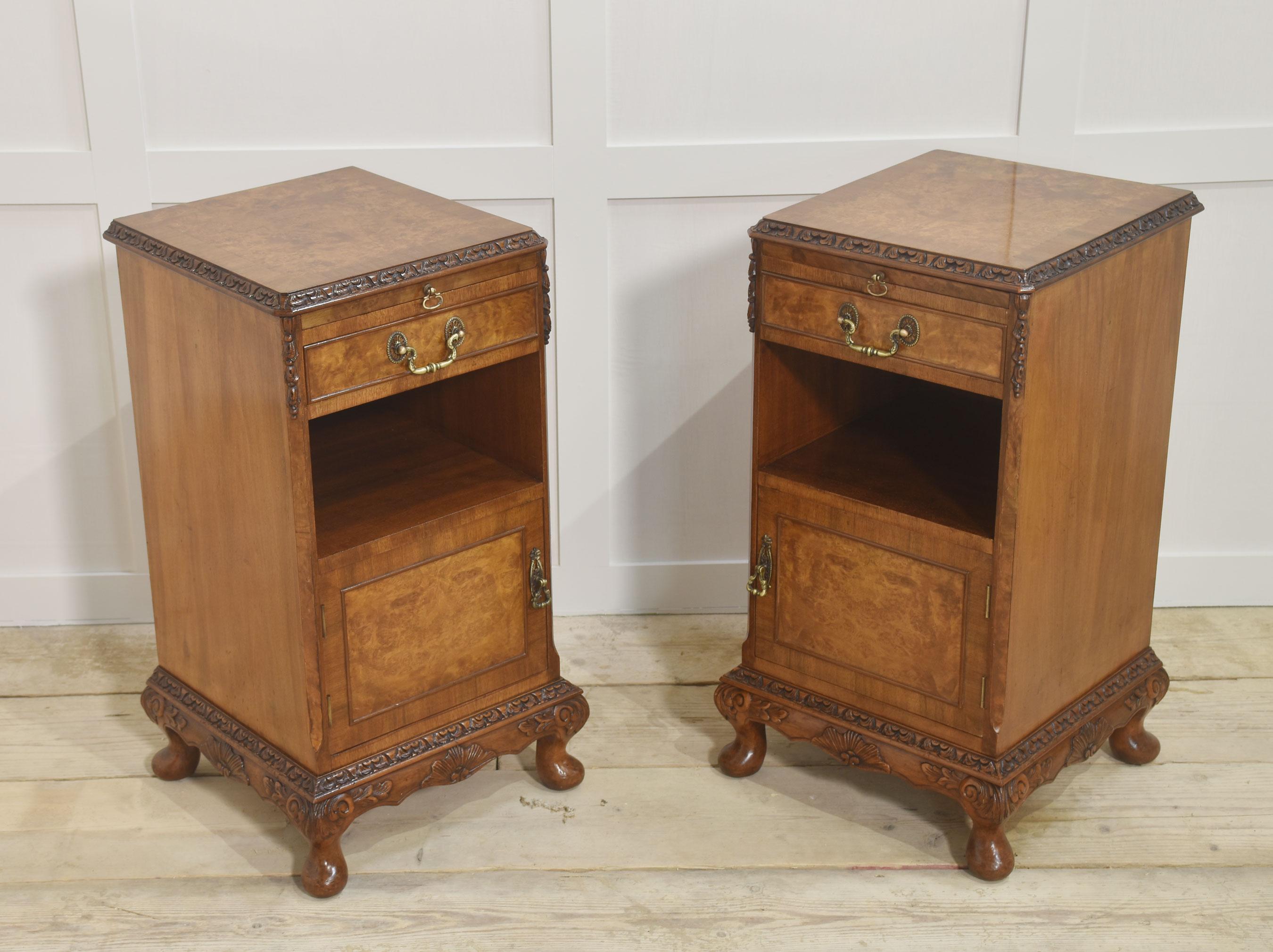 Pair of bedside cabinets, each having well-figured tops, to the carved moulded edge above pull-out mirrored slide and short drawer below. To the open recessed cupboard above a panelled door opening to reveal further storage space. All raised on