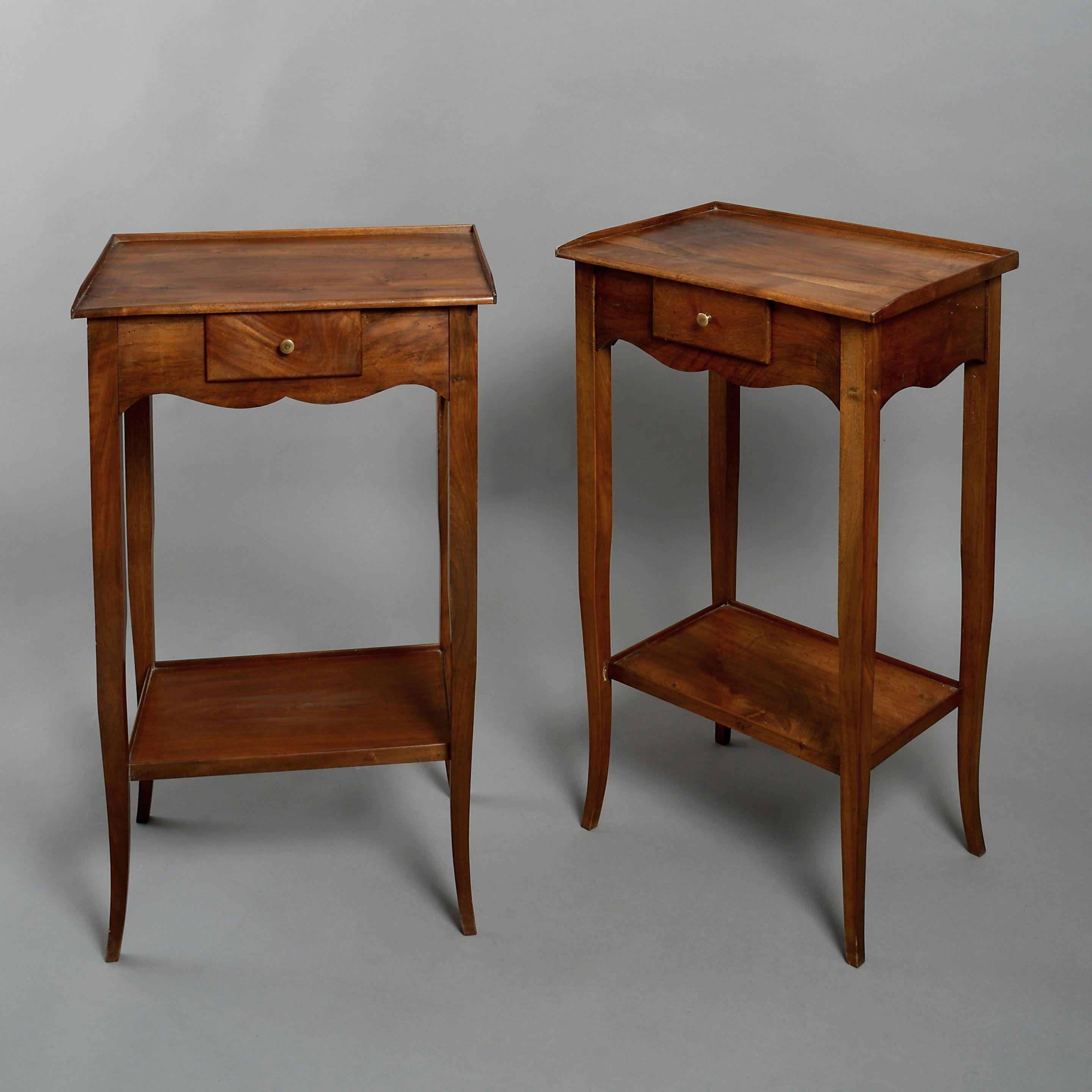 A pair of early 20th century walnut end tables or night stands in the Louis XV manner, each with a rectangular top set above a small central drawer within a shaped apron, all raised on square tapering legs and having a lower shelf.