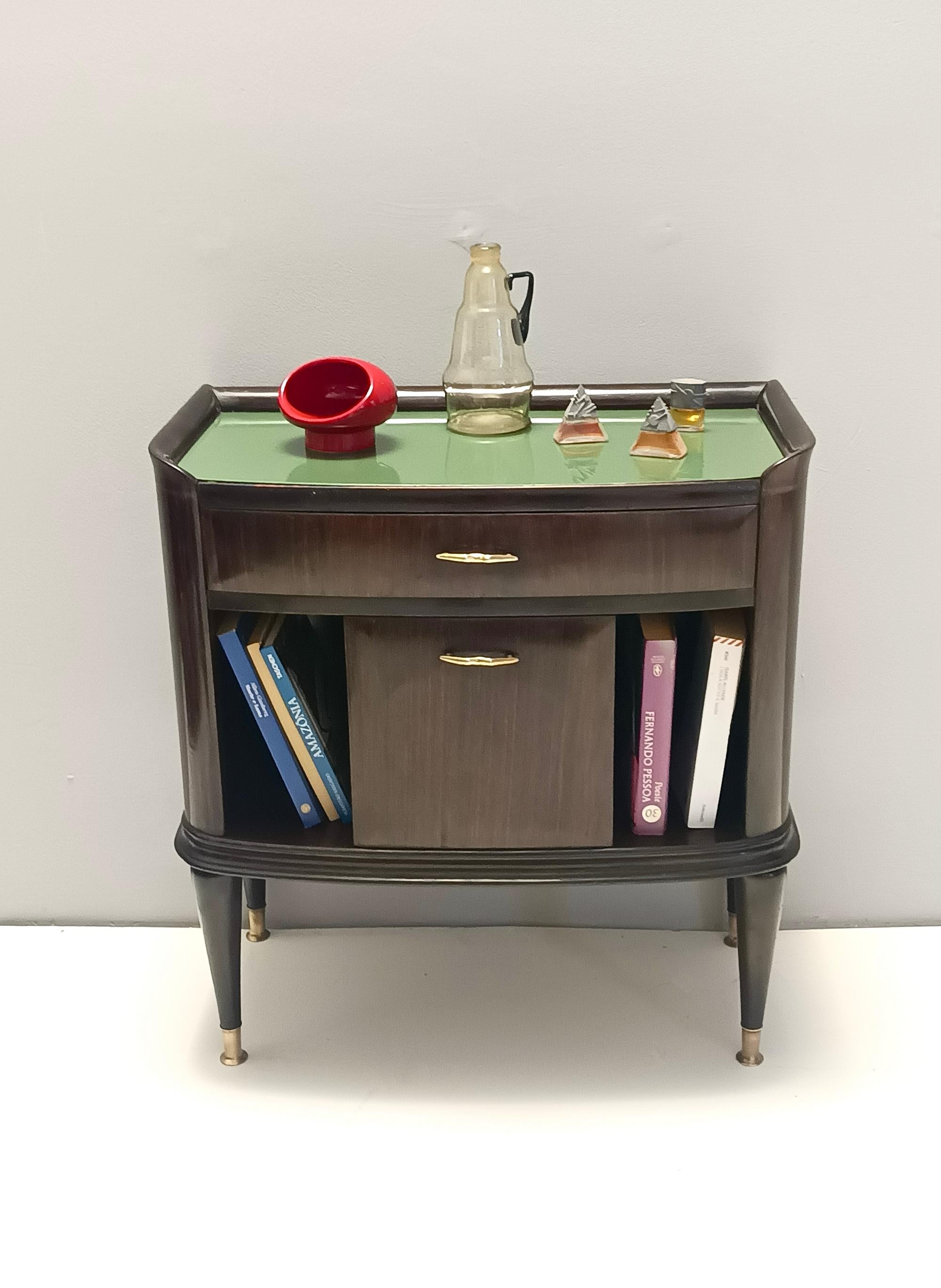 Made in Italy, 1950s.
They are made in ebonized walnut and beech, and feature brass handles and feet caps and a green back-painted glass top.
These nightstands may show slight traces of use since they're vintage, such as a tiny flaw of one of the
