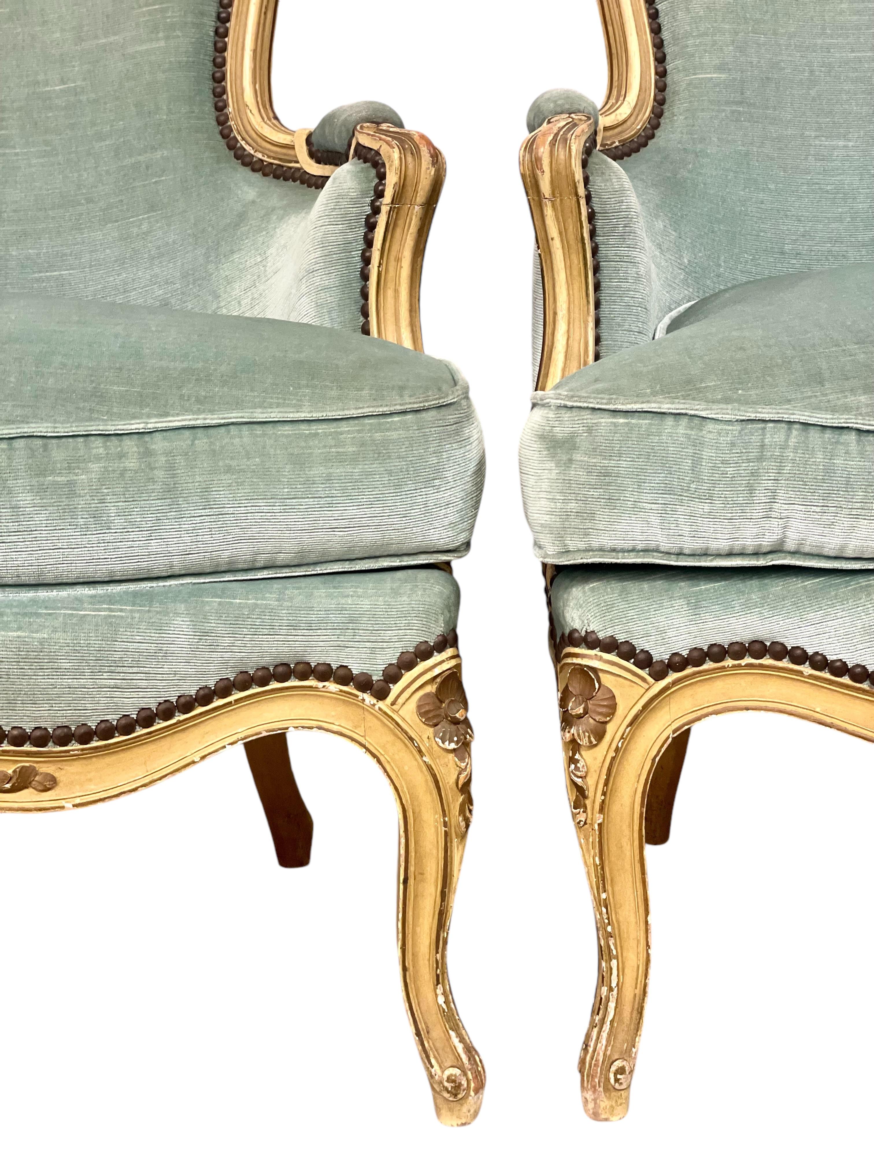 Cette paire exquise de fauteuils de style Louis XV respire l'élégance et le savoir-faire intemporels. Fabriquées en noyer massif, avec un cadre en bois doré magnifiquement sculpté, ces chaises présentent des motifs floraux complexes et des courbes