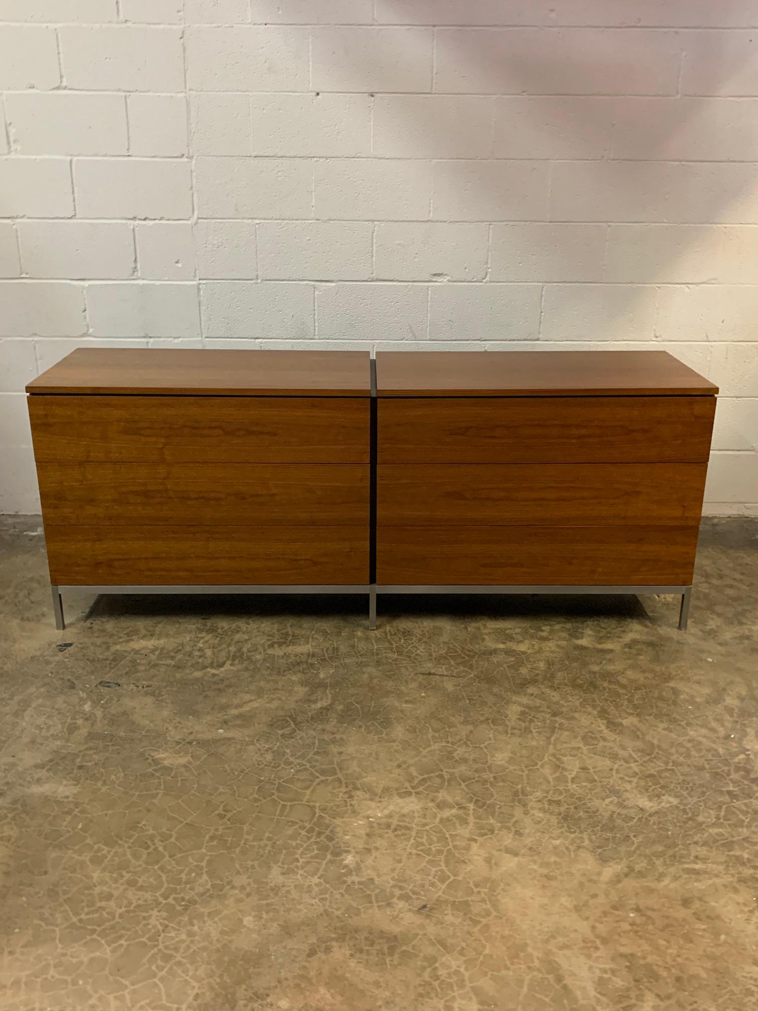 A matching pair of early walnut dressers on brushed nickel frames designed by Florence Knoll for Knoll. Each cabinet has six drawers with removable dividers. When placed together you have a 12 ft cabinet.
