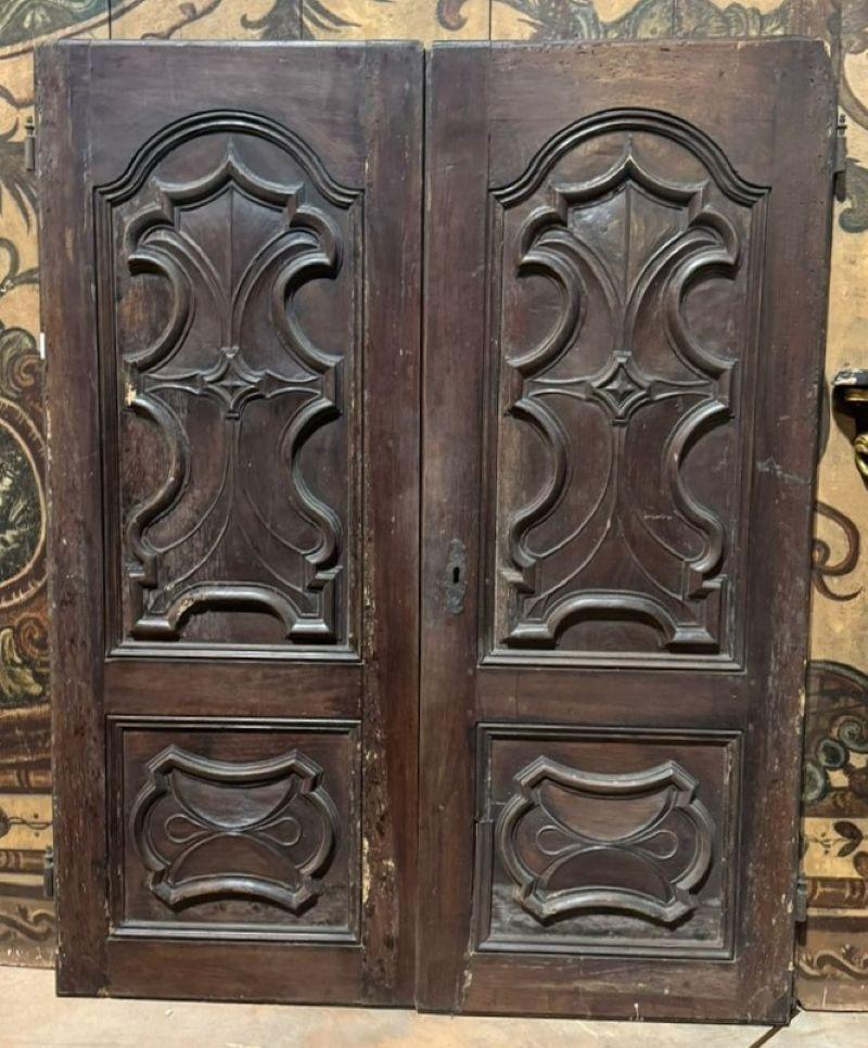 Antique pair of walnut doors with carved Baroque panels, probably originally designed as wardrobe doors, adaptable to panels or small doors, from Italy and original from the 18th century. Smooth back.
Double door dimensions: W 122 x H 156 cm