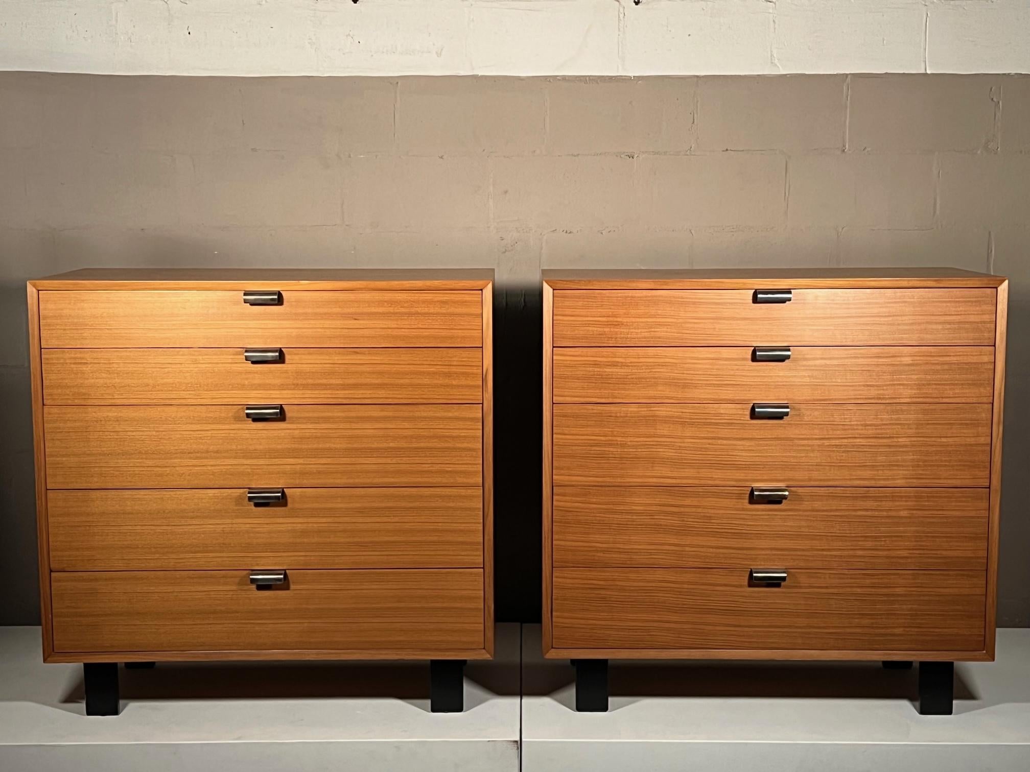 A pair of walnut George Nelson 5 drawer dressers with J shaped handles. Manufactured by Herman Miller from the Basic Cabinet Series in the 1950's. This particular pair is very clean with lighter walnut finish and clear wavy graining. Original