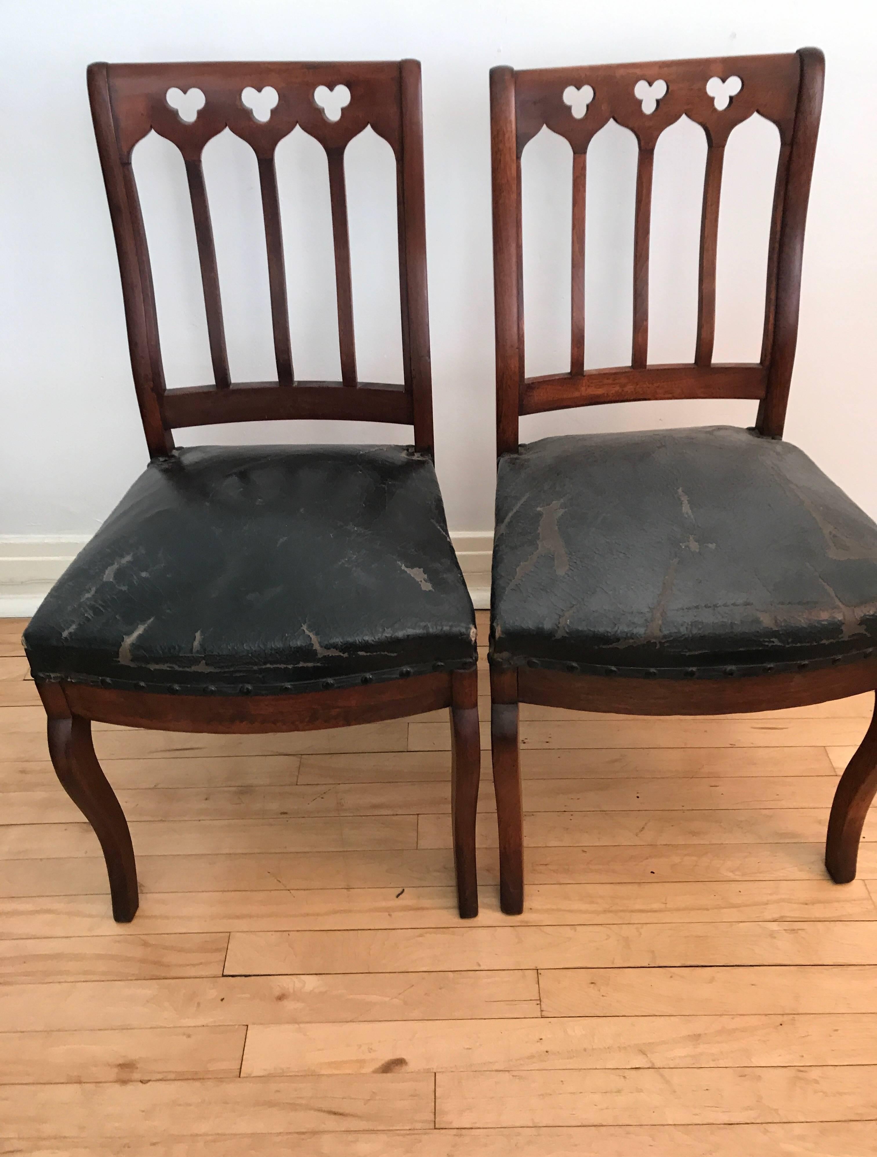A pair of American 19th century Gothic Revival walnut hall chairs. The side chairs are still upholstered in their original leather.